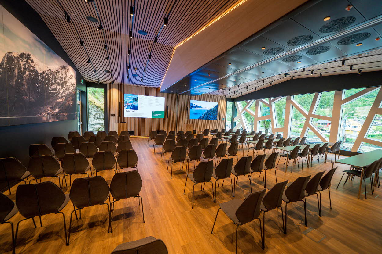 Fretheim Hotels store konferanselokale i kinooppsett. Store vinduer med geometriske former i hvitt, to store skjermer i front og stort bilde på en vegg.