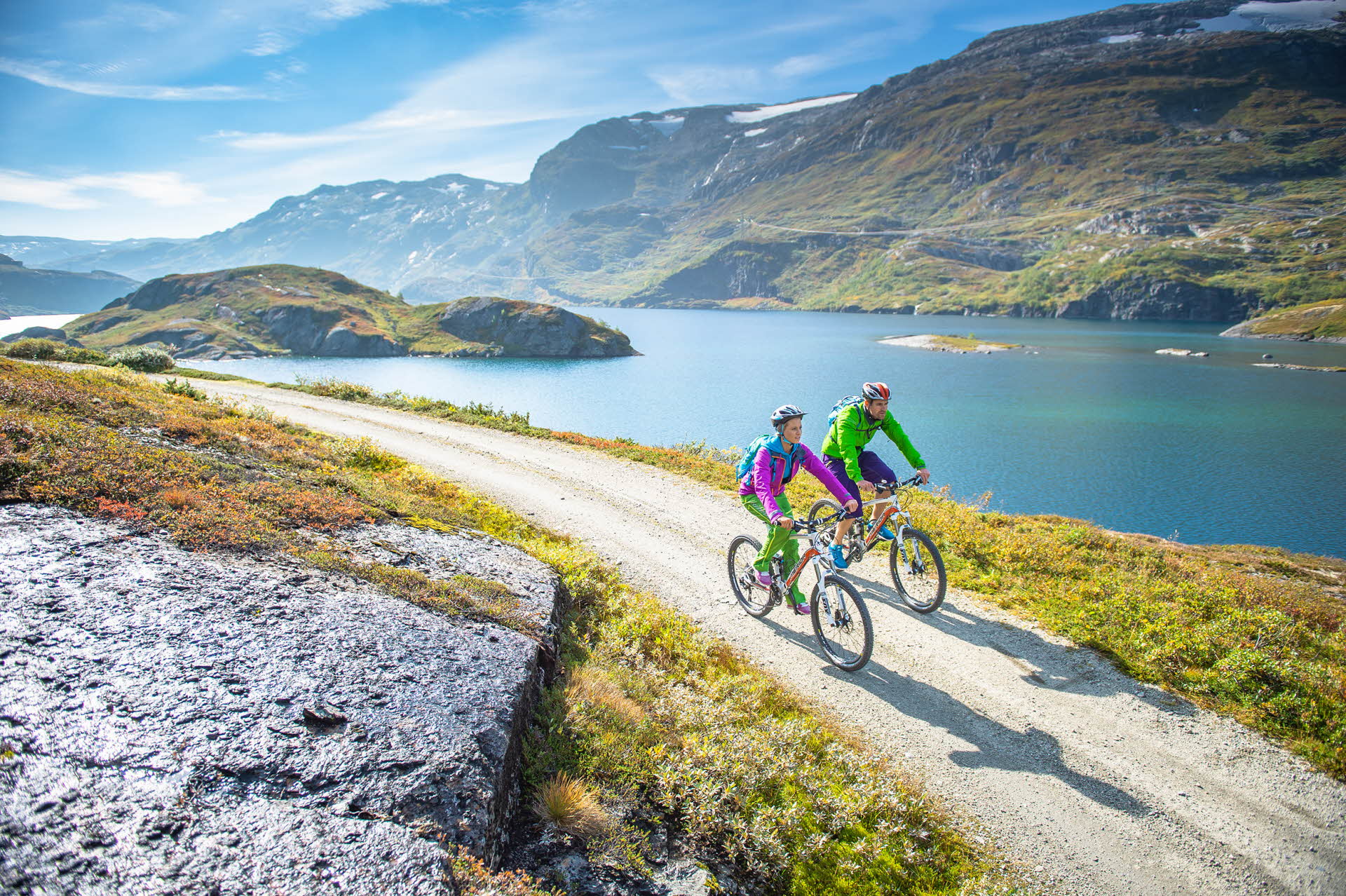 A man and woman cycling along a stream at Rallarvegen