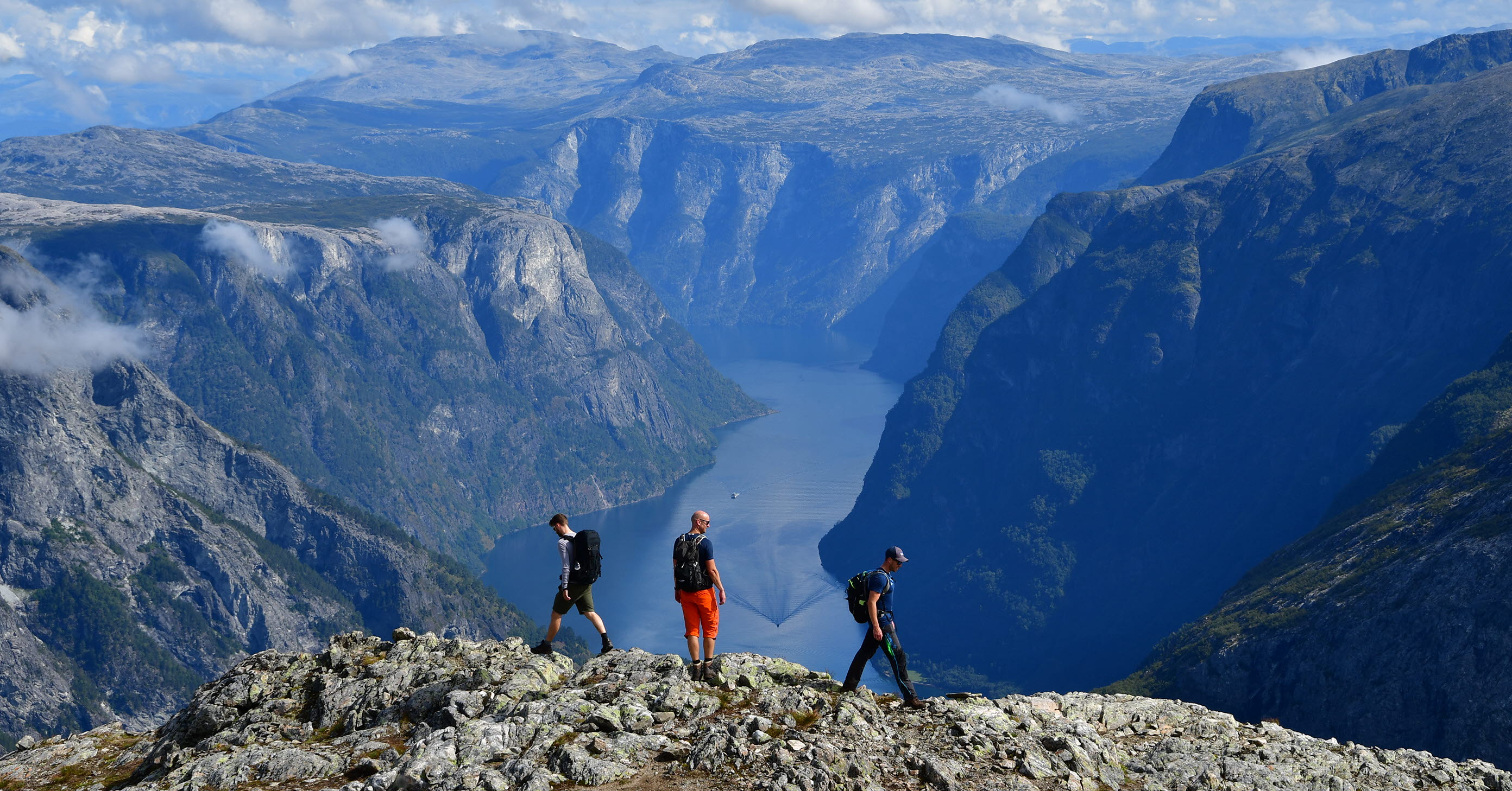 Three tourists on the edge of Bakkanosi above the Nærøyfjord