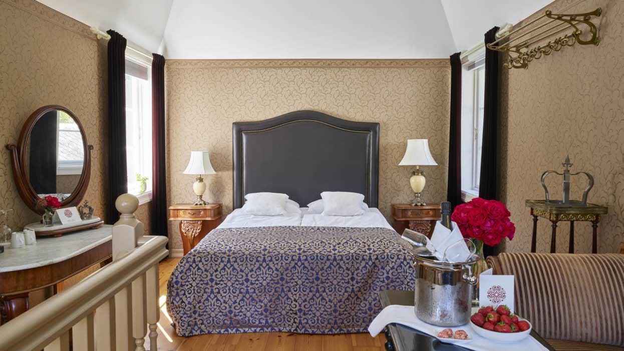Le niveau supérieur de la suite de la tour du Fretheim Hotel, avec champagne et fraises sur la table et lit fait en arrière-plan