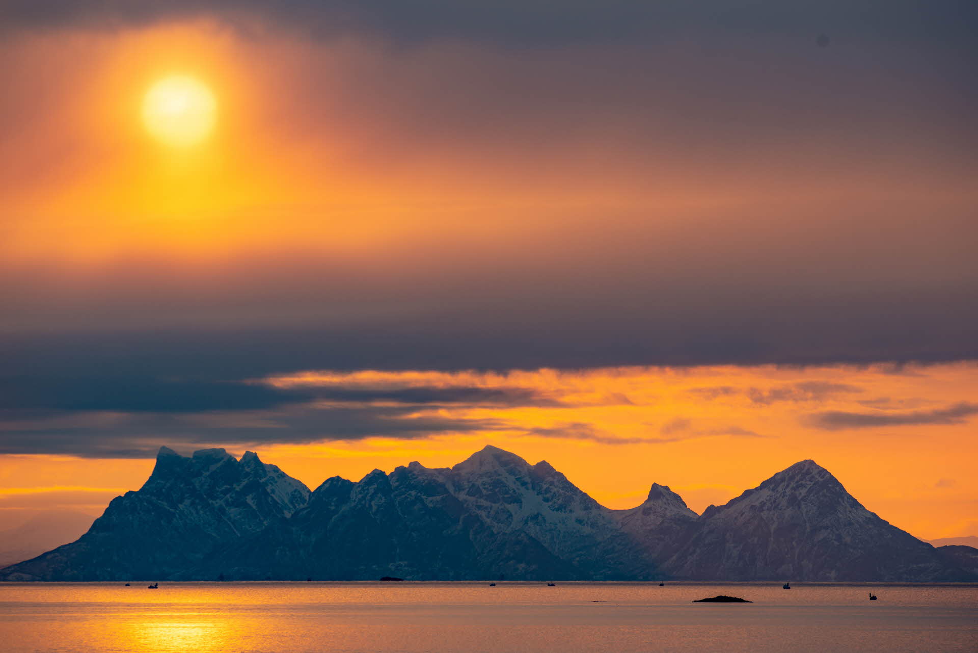 Die Sonne geht über einer bergigen Insel auf den Lofoten unter.