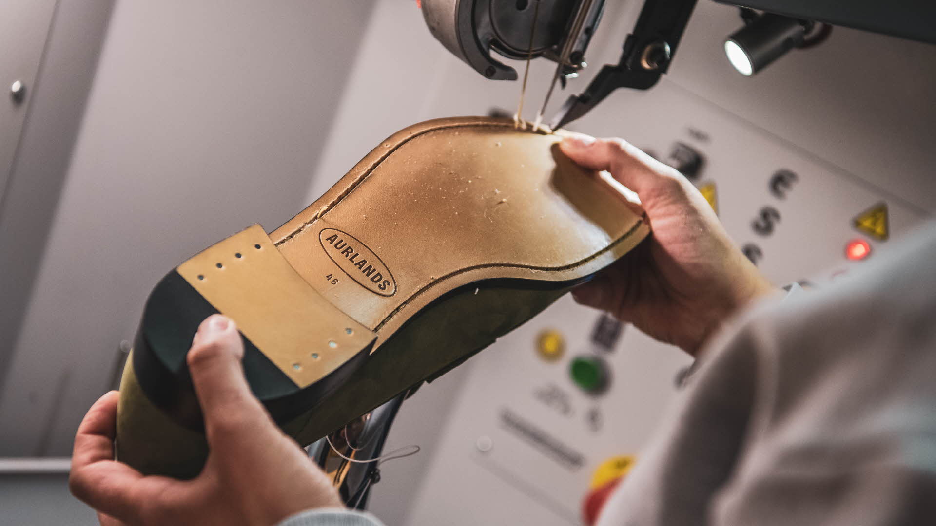 Worker is stitching underside sole of Aurland shoe. Aurlands new logo is popping in the mini spotlight attached to sewing machine.