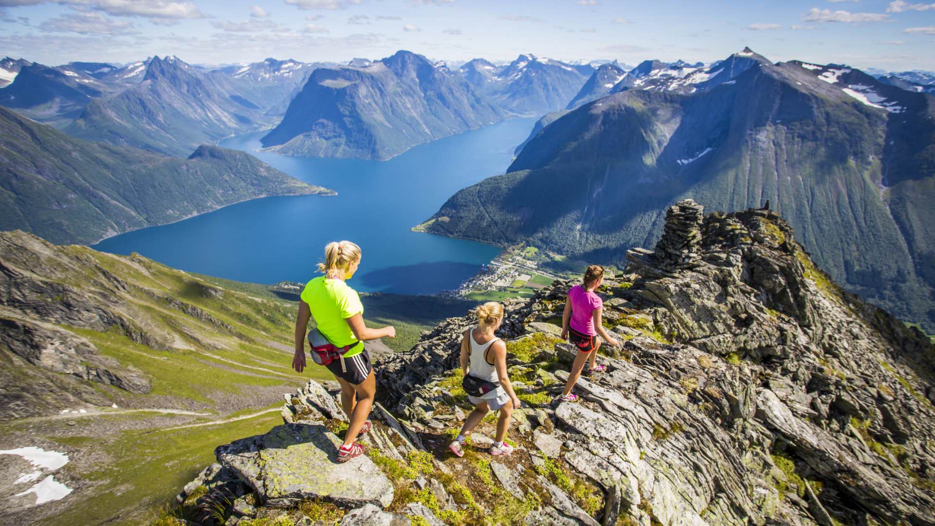 Trois femmes randonnent sur un sommet au-dessus du Hjørundfjord.
