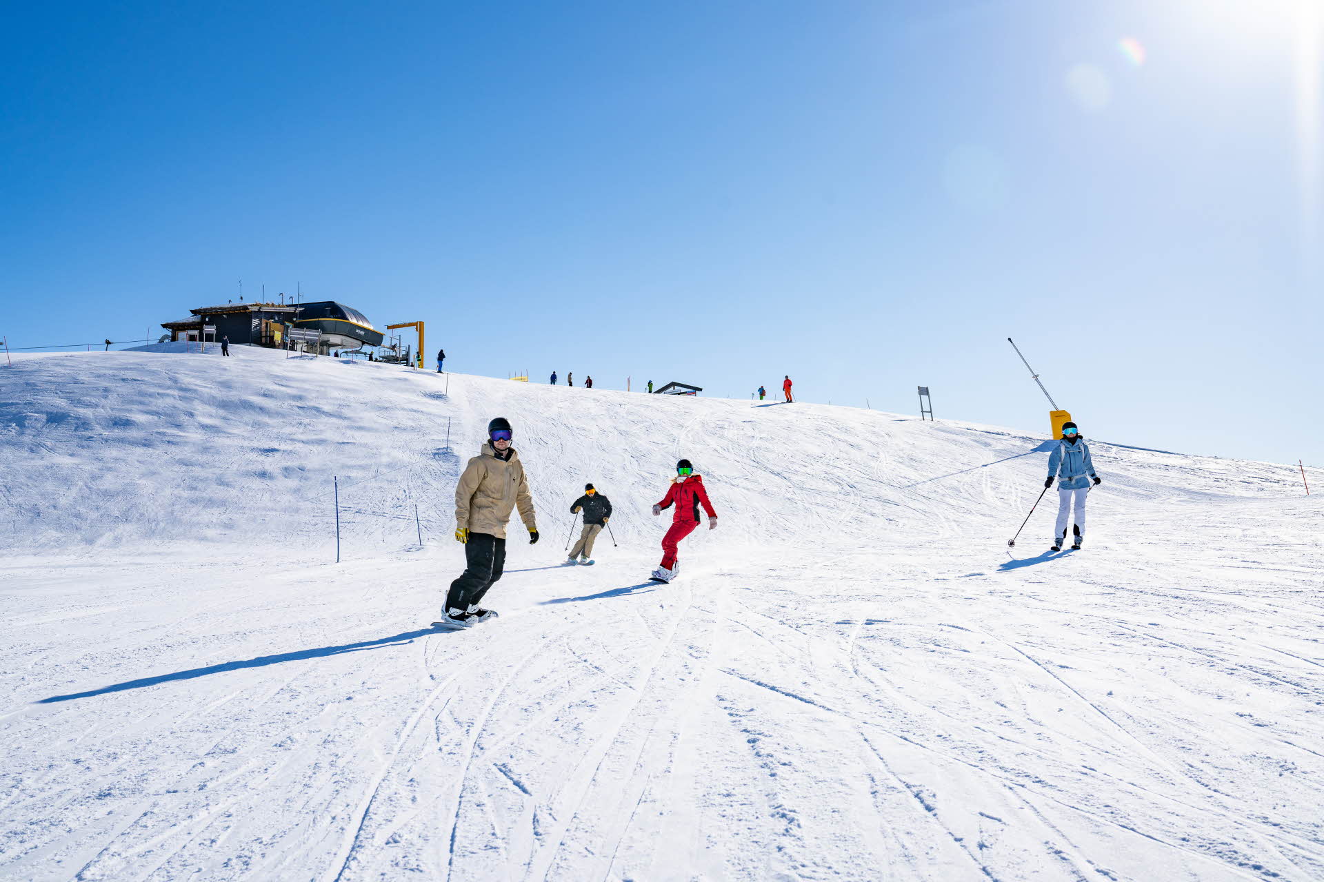 Menschen beim Skifahren und Snowboarden auf einer Piste in Myrkdalen. 