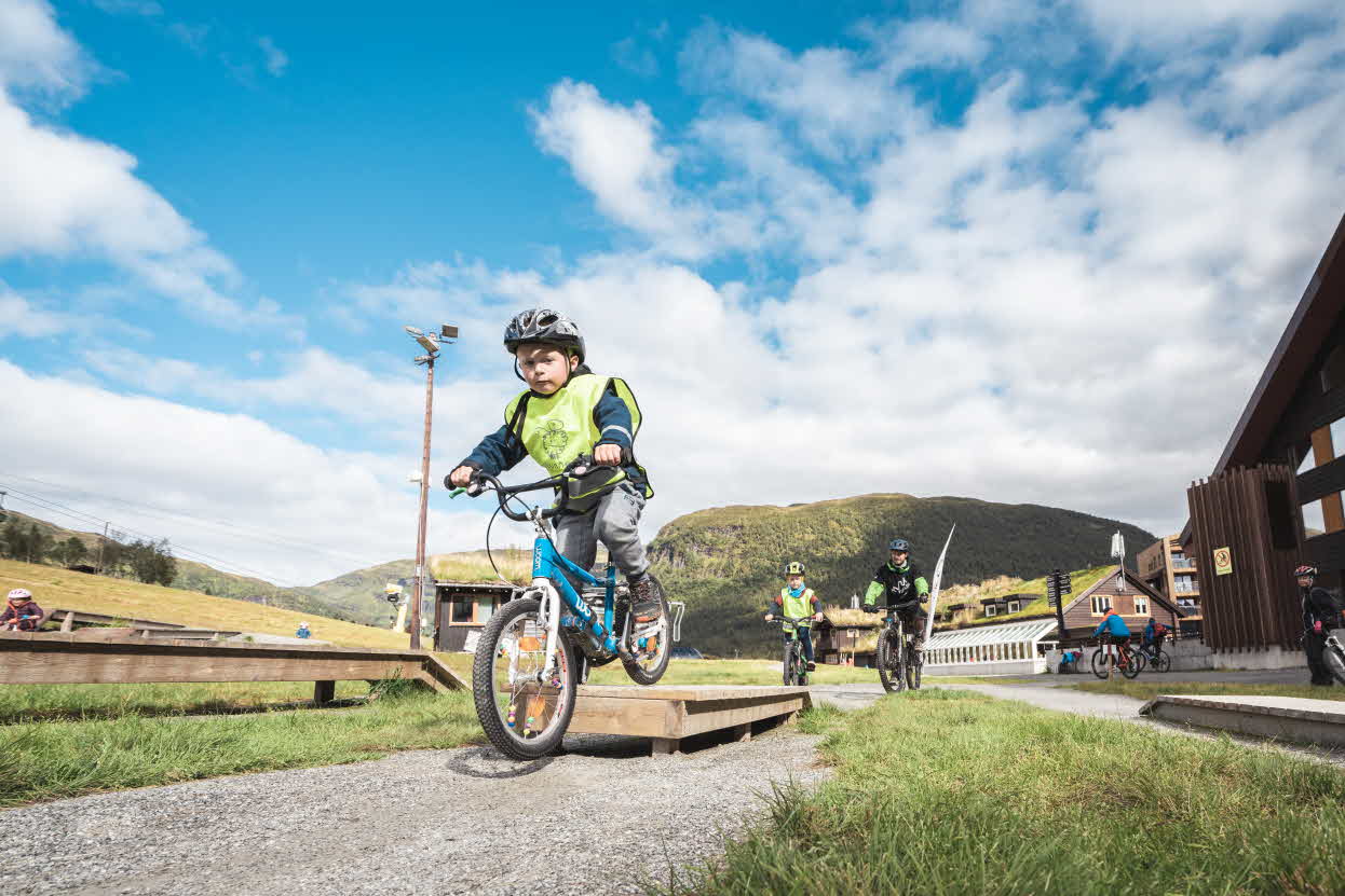 Ein kleiner Junge fährt mit dem Rad über ein Hindernis auf der Mountainbike-Trainingsstrecke in Myrkdalen
