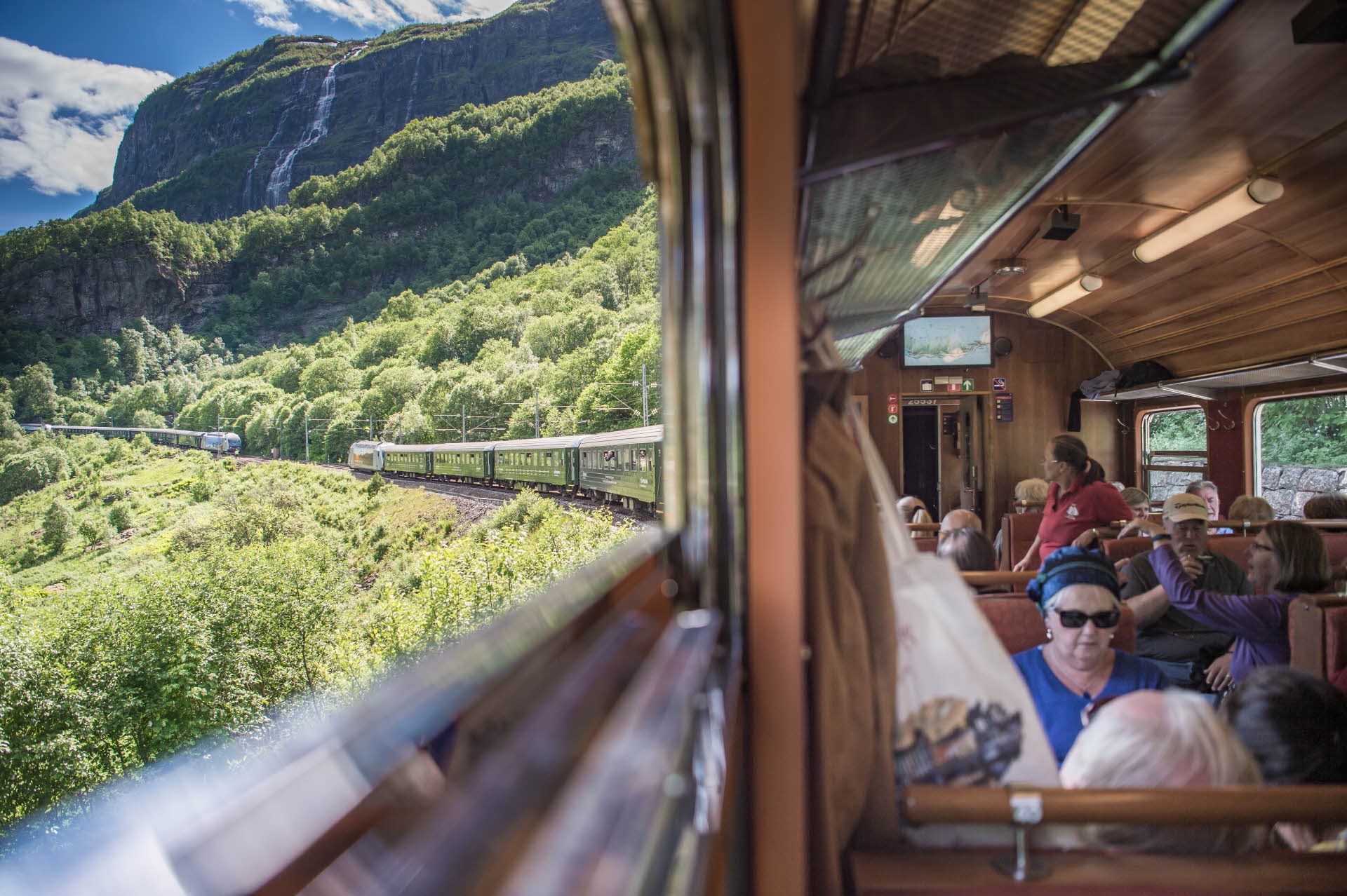 Blick aus dem Fenster der Flåmbahn auf das Flåmsdalen und einen entgegenkommenden Zug