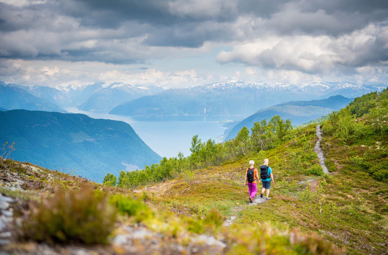 Two women walking on a path above the Sognefjord