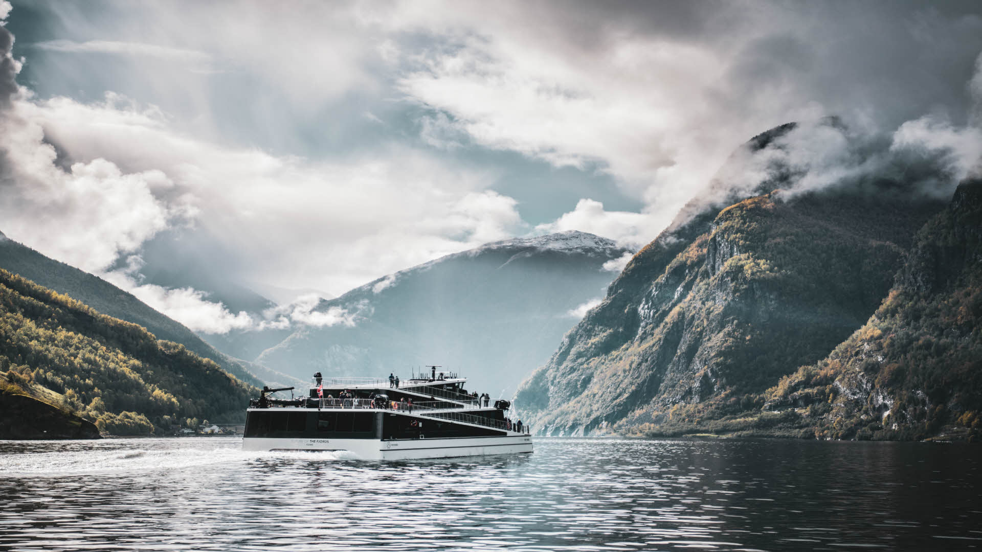 The electric vessel Future of The Fjords sailing through the calm UNESCO listed Naeroyfjord on a sunny autumn day