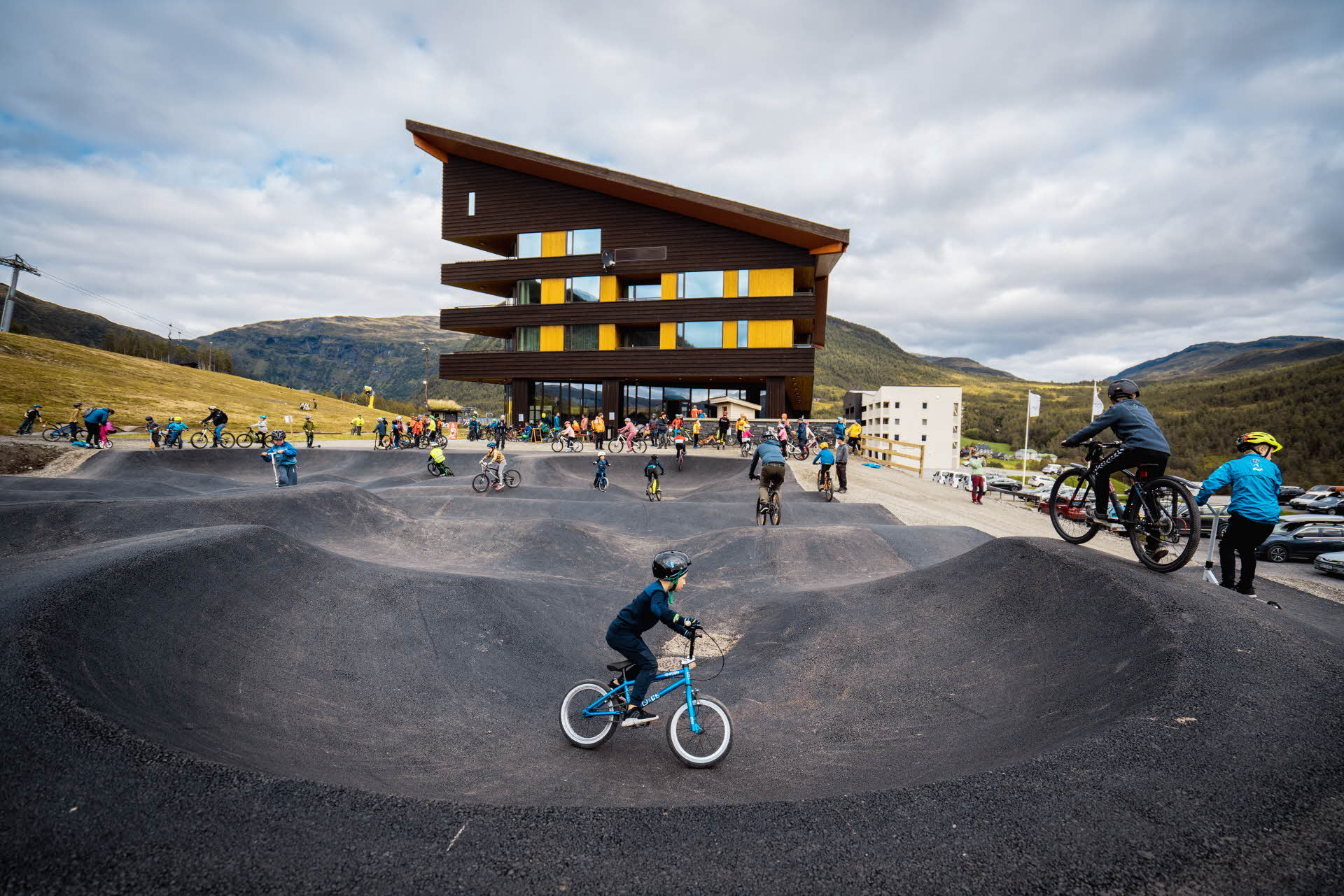 Children and adults cycle on the pumptrack outside the Myrkdalen Hotel