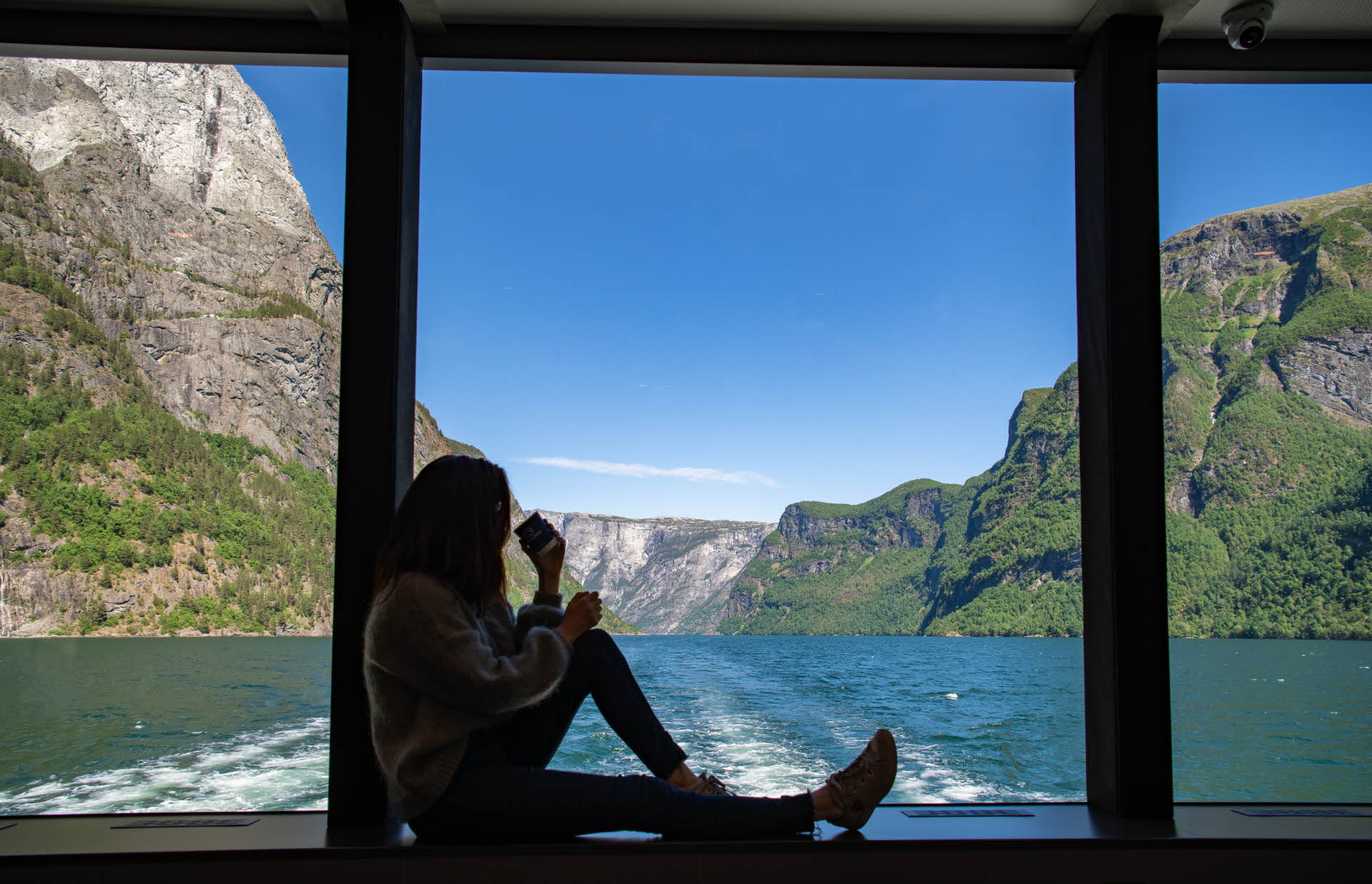 Kvinne sitter i vinduskarmen på Future of The Fjords i Aurlandsfjorden