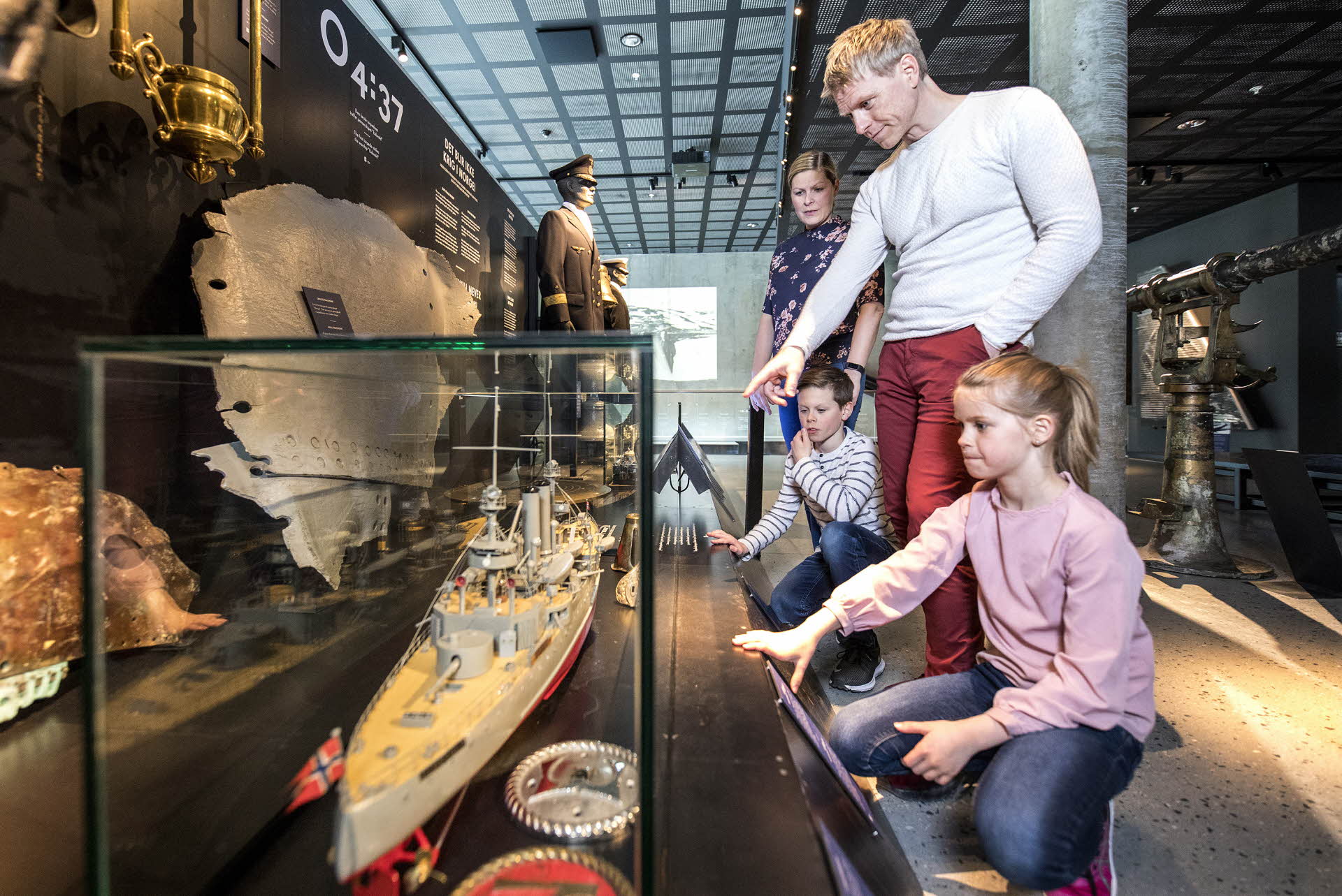 一家人站在纳尔维克战争博物馆的一艘军舰复制品旁。