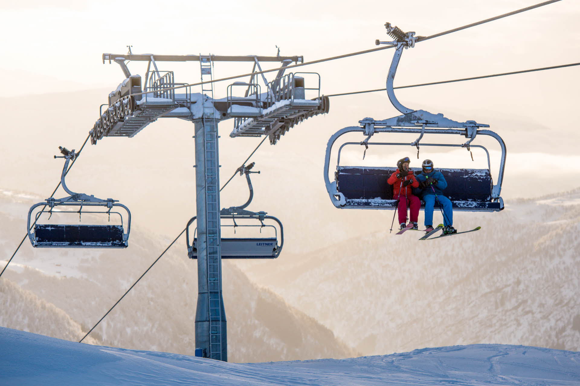 两个人戴着滑雪板坐在迈克达林山度假区 (Myrkdalen Mountain Resort) 的雪场缆车上