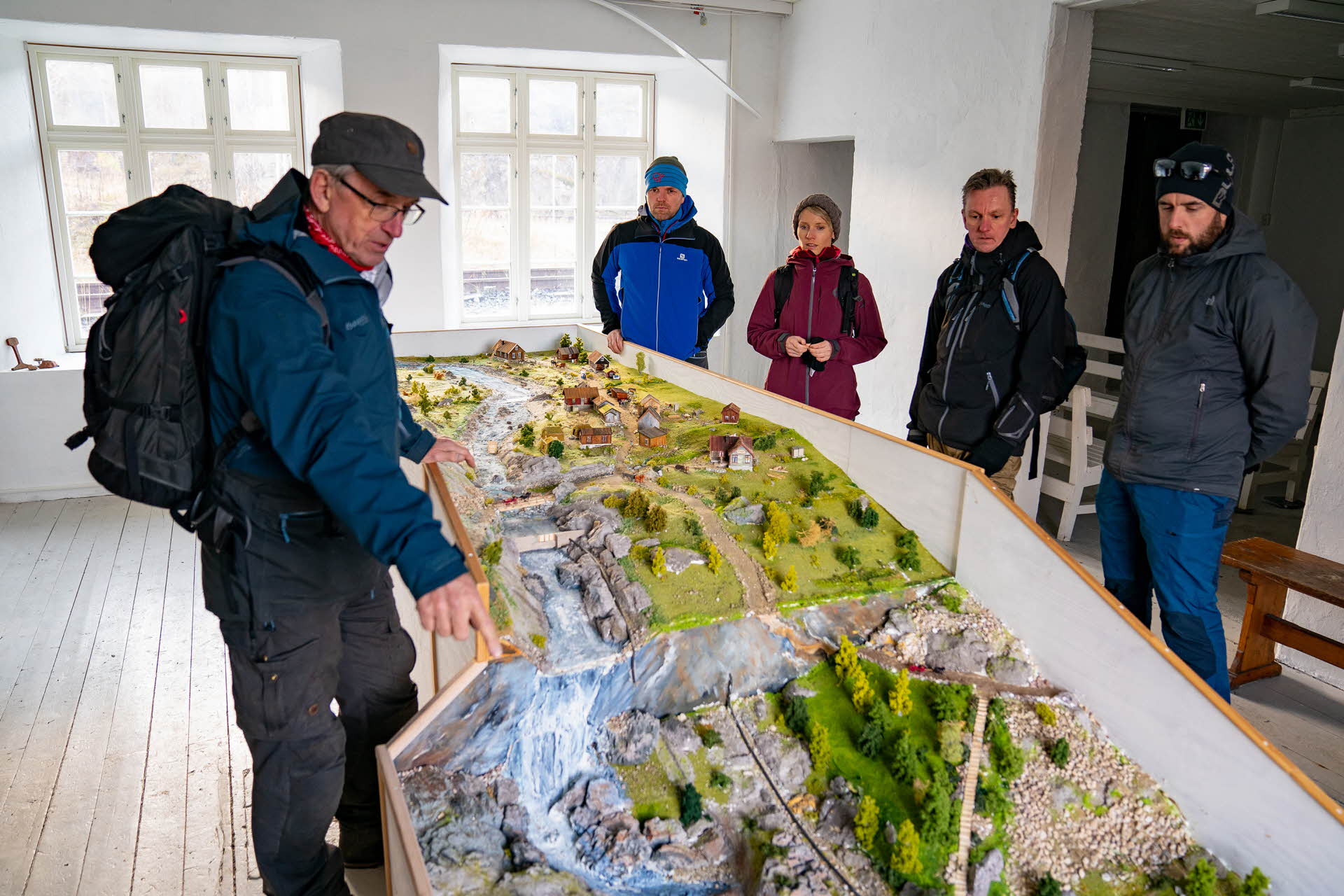 A guide showing a model of the construction site of the Ofot Line to a group of three men and a woman.