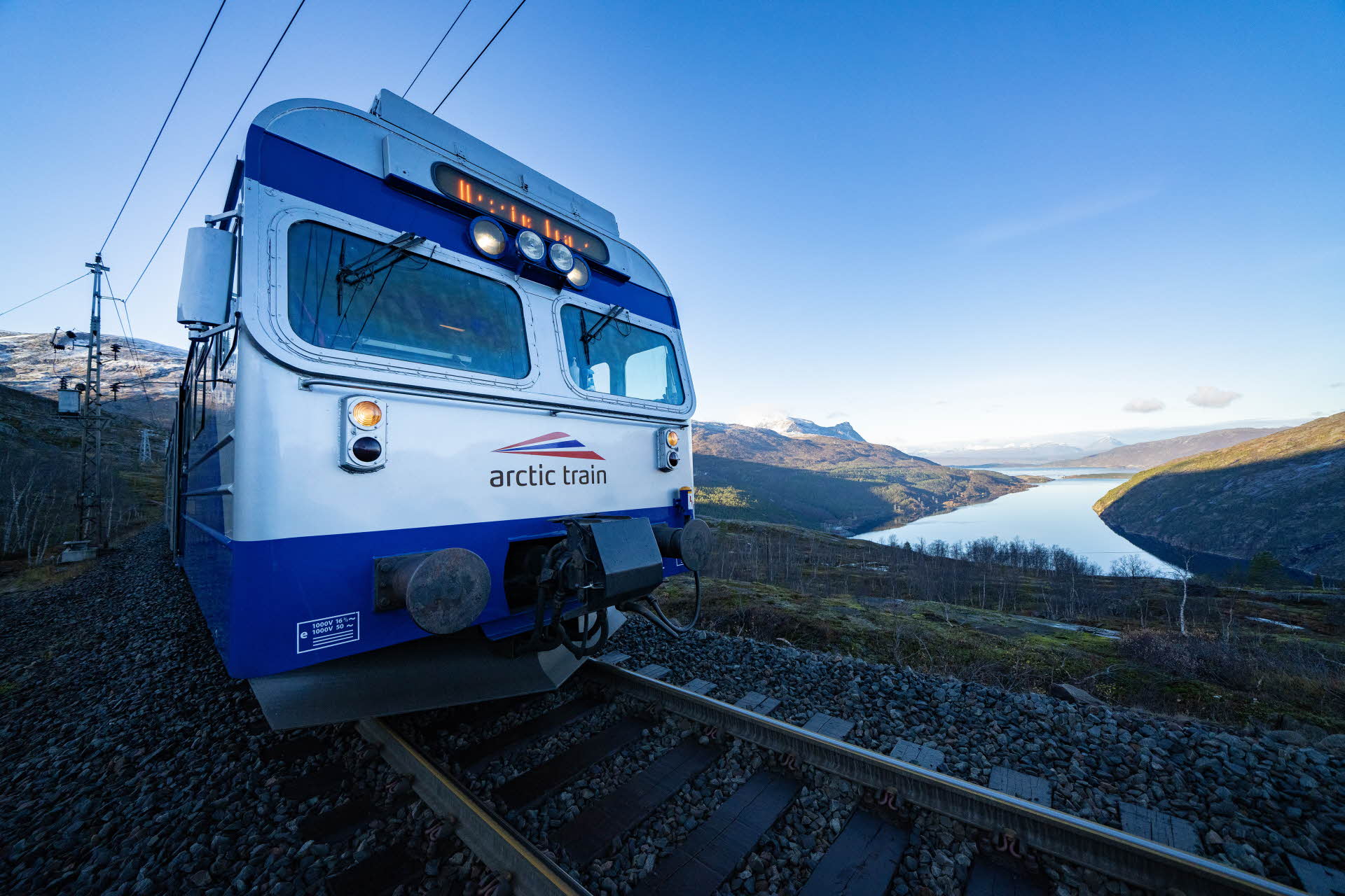 Det blå lokomotivet til The Arctic Train på nært hold, med Rombaken fjord under. 