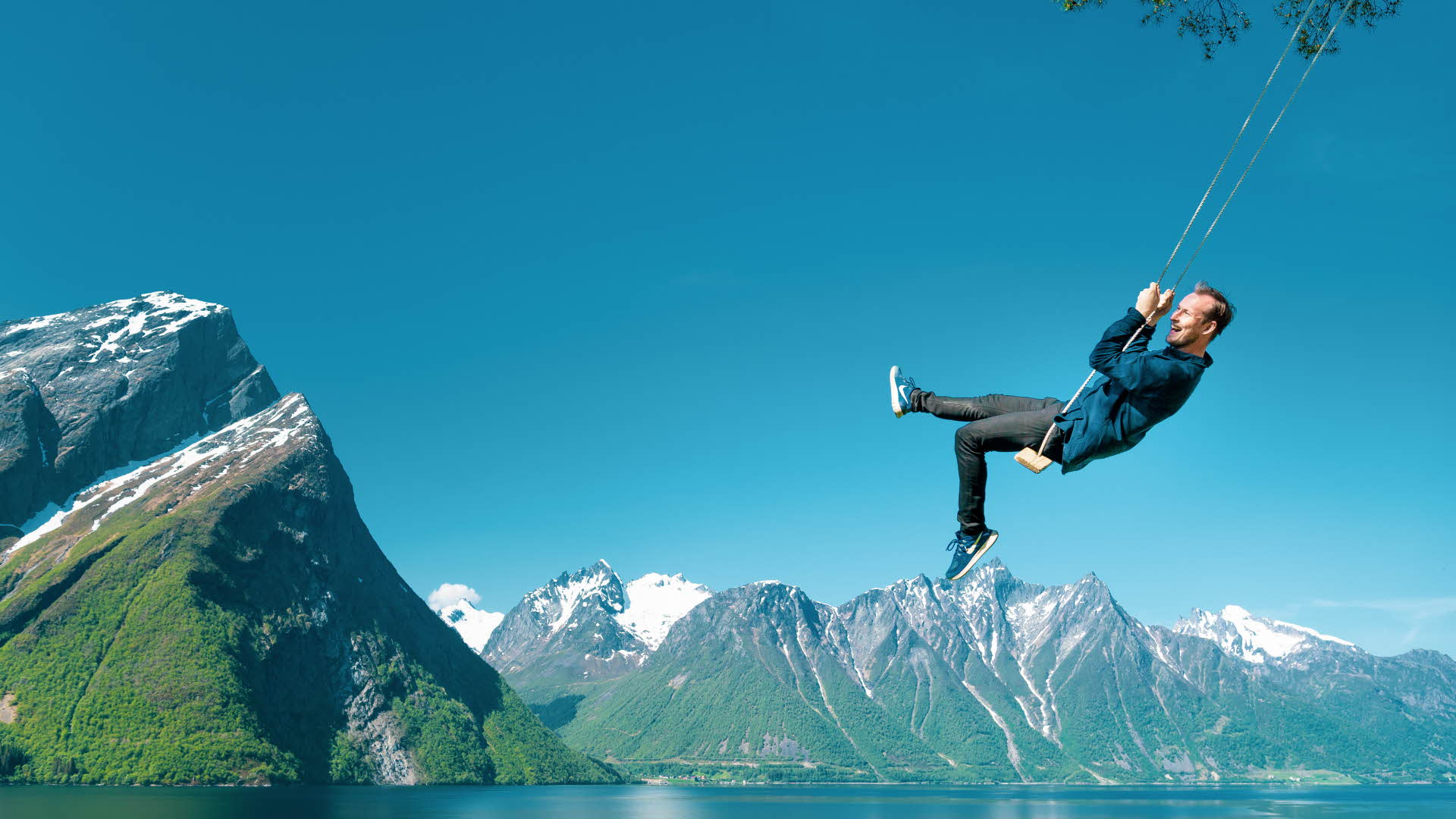 Un hombre divirtiéndose en un columpio junto a Hjørundfjord