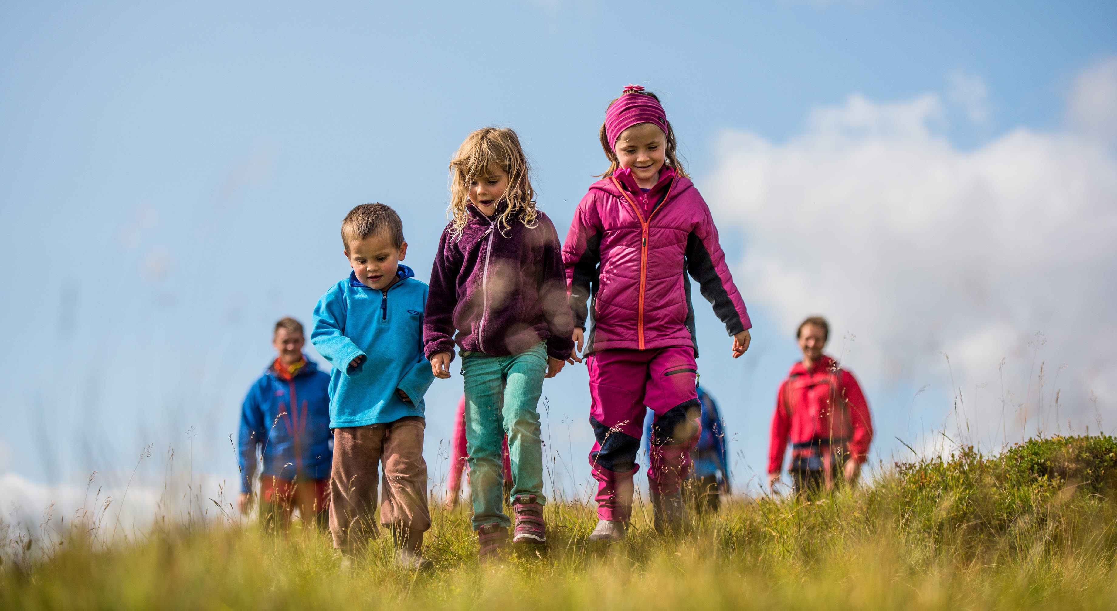 Trois enfants en excursion à Myrkdalen, avec des adultes marchant derrière eux