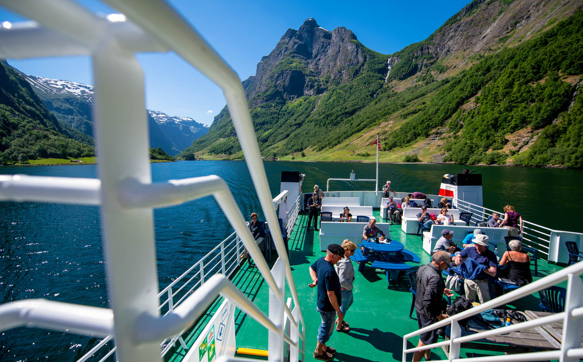 Des gens sur le pont-terrasse d’un ferry classique de croisière dans le Sognefjord profitant des paysages spectaculaires du Naeroyfjord