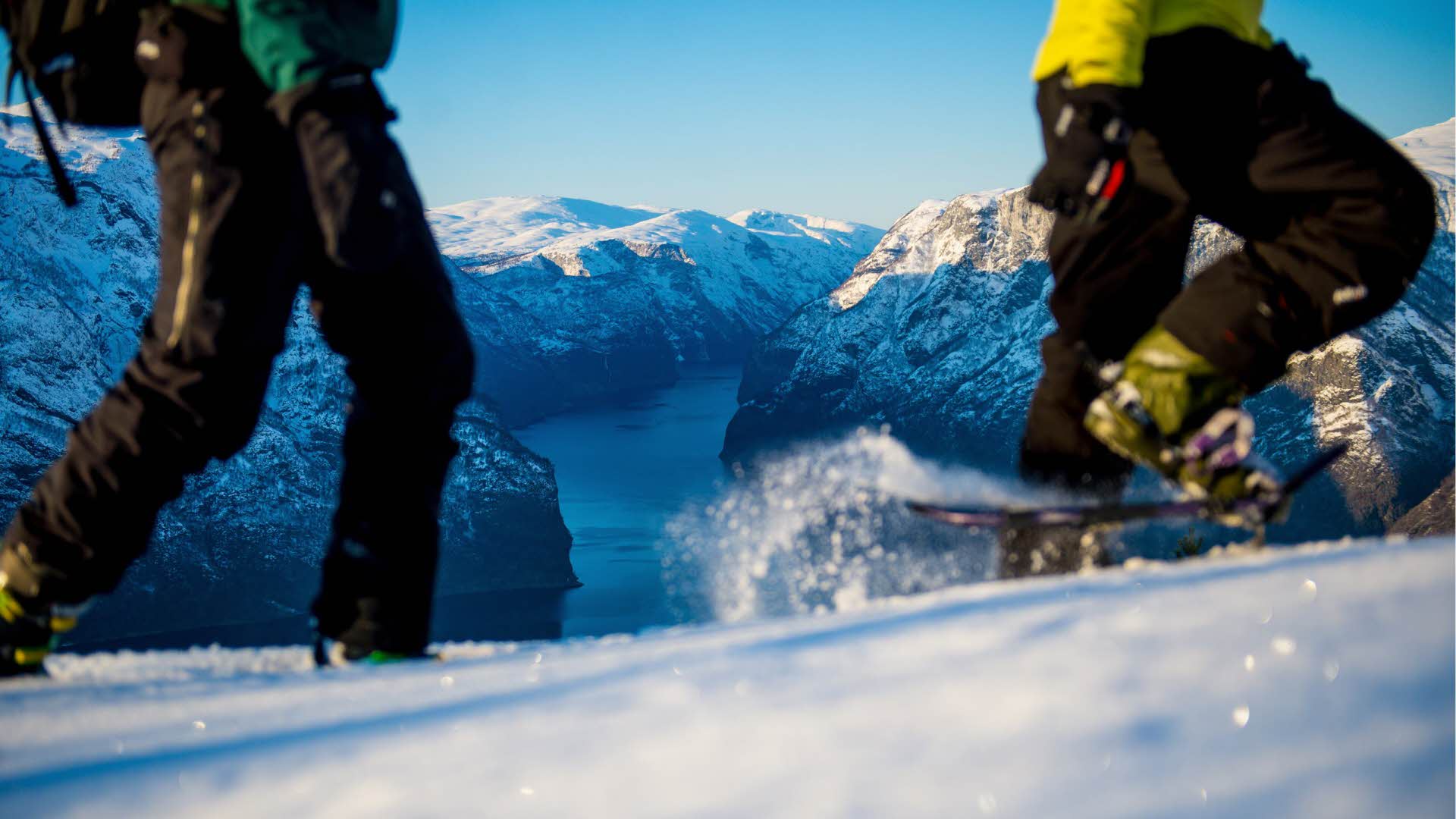 Die Beine von zwei Personen beim Schneeschuhwandern über dem Aurlandsfjord