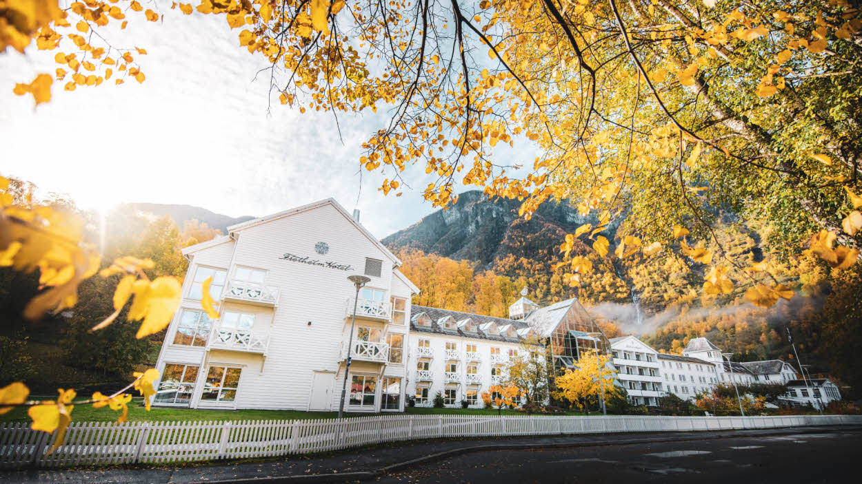 Hotel Fretheim visto a través de unas hojas amarillas, con la montaña de fondo.