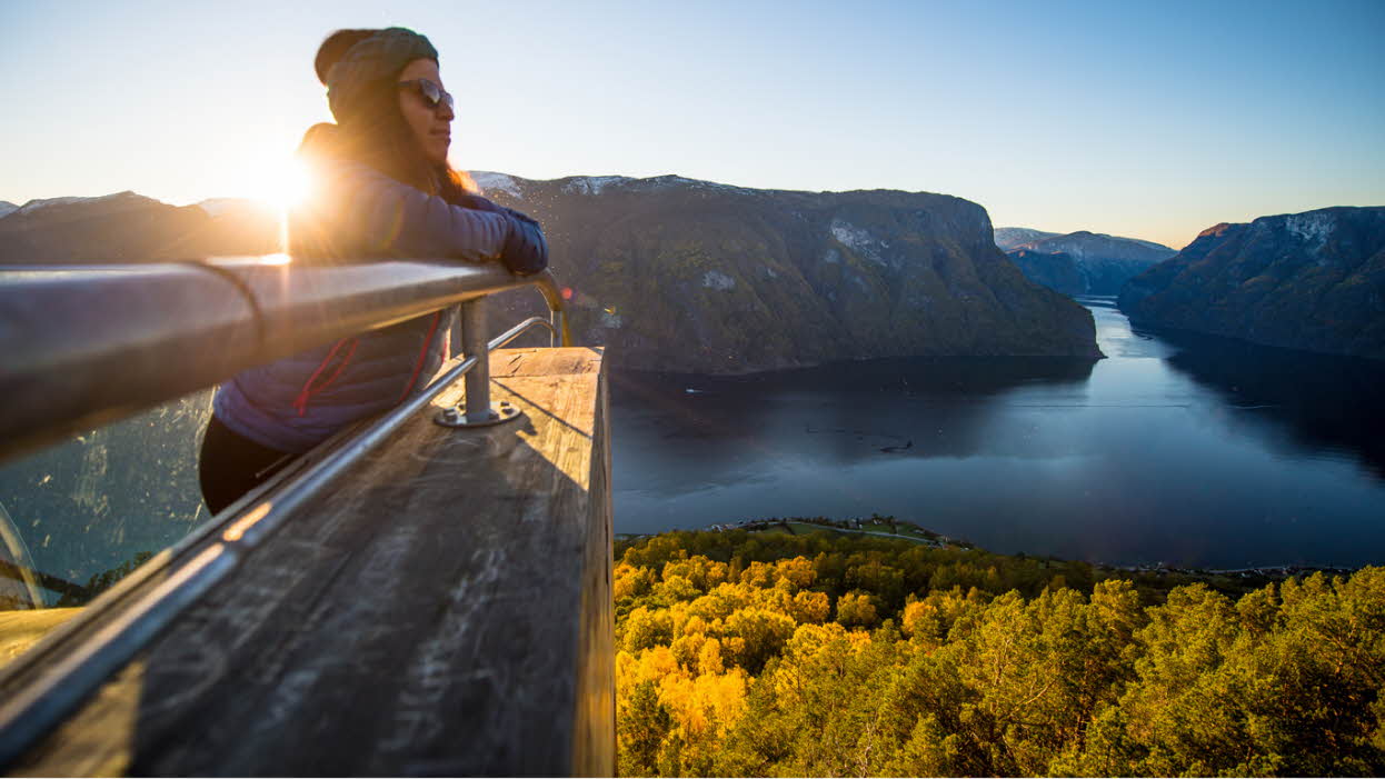 Une femme profitant du coucher de soleil sur l’Aurlandsfjord depuis le Stegastein