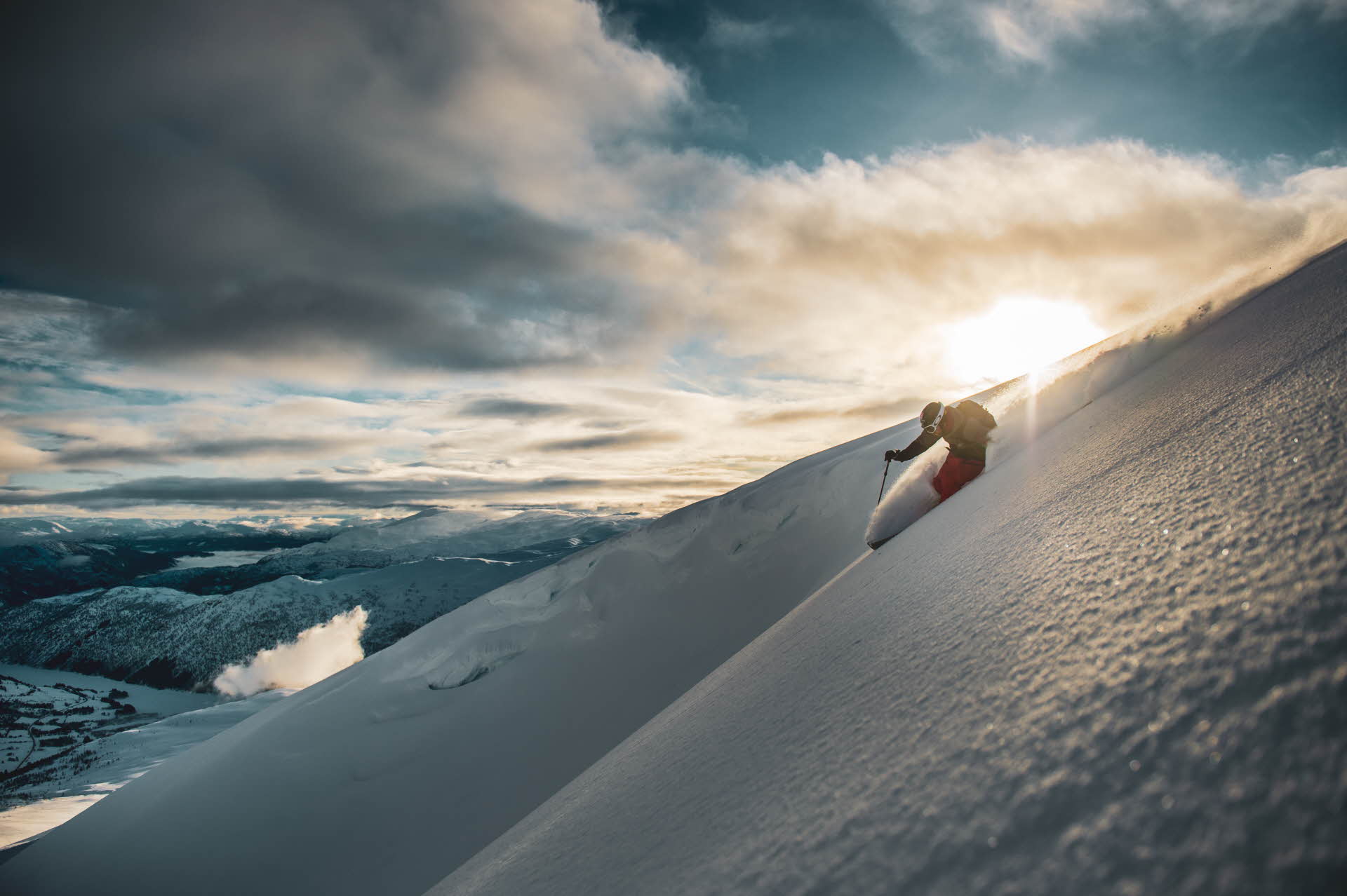 En person står på ski i pudder over Myrkdalen