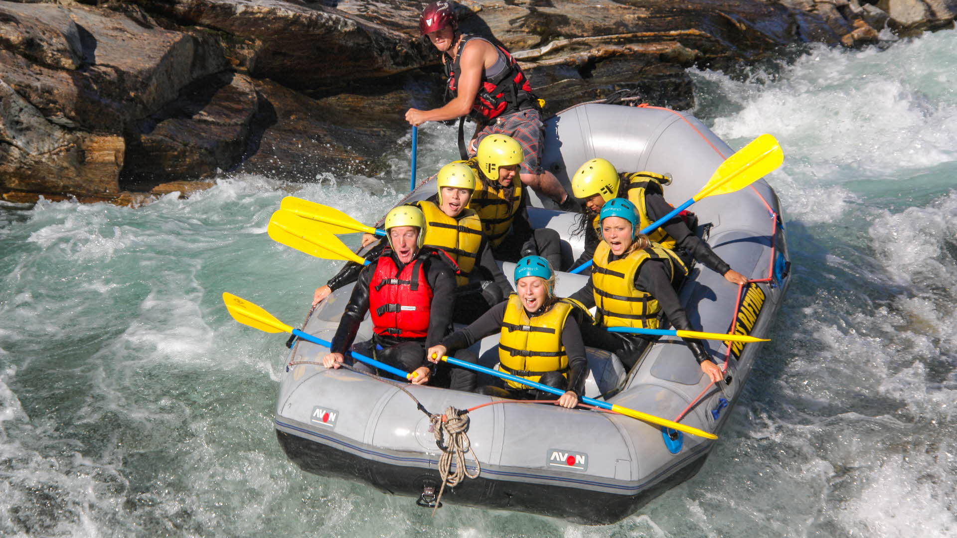 A raft with six passengers and a guide going down a rapid on a Voss river.