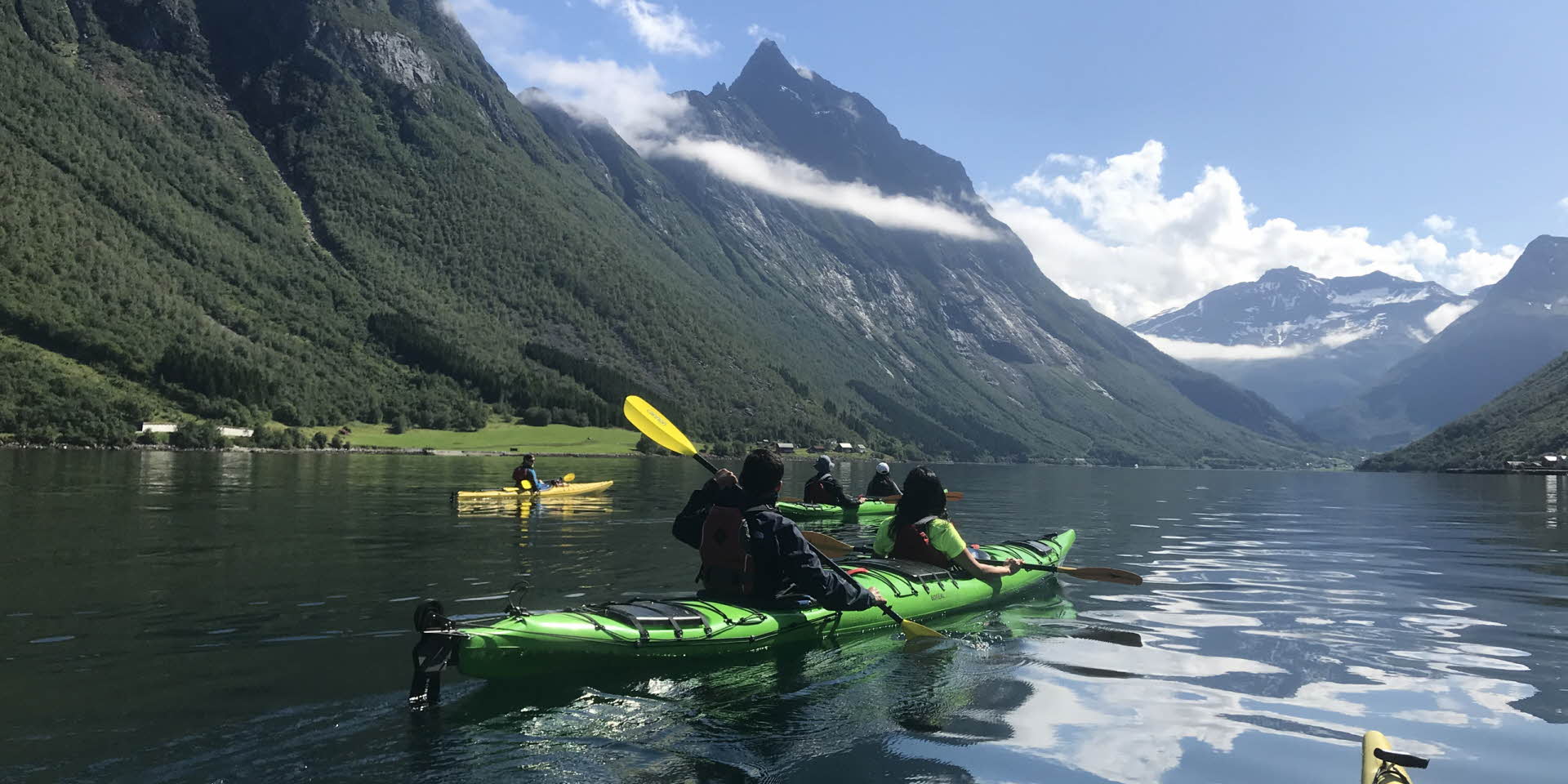 People kayaking in inner Hjorundfjord surronded with dramatic fjord landscape