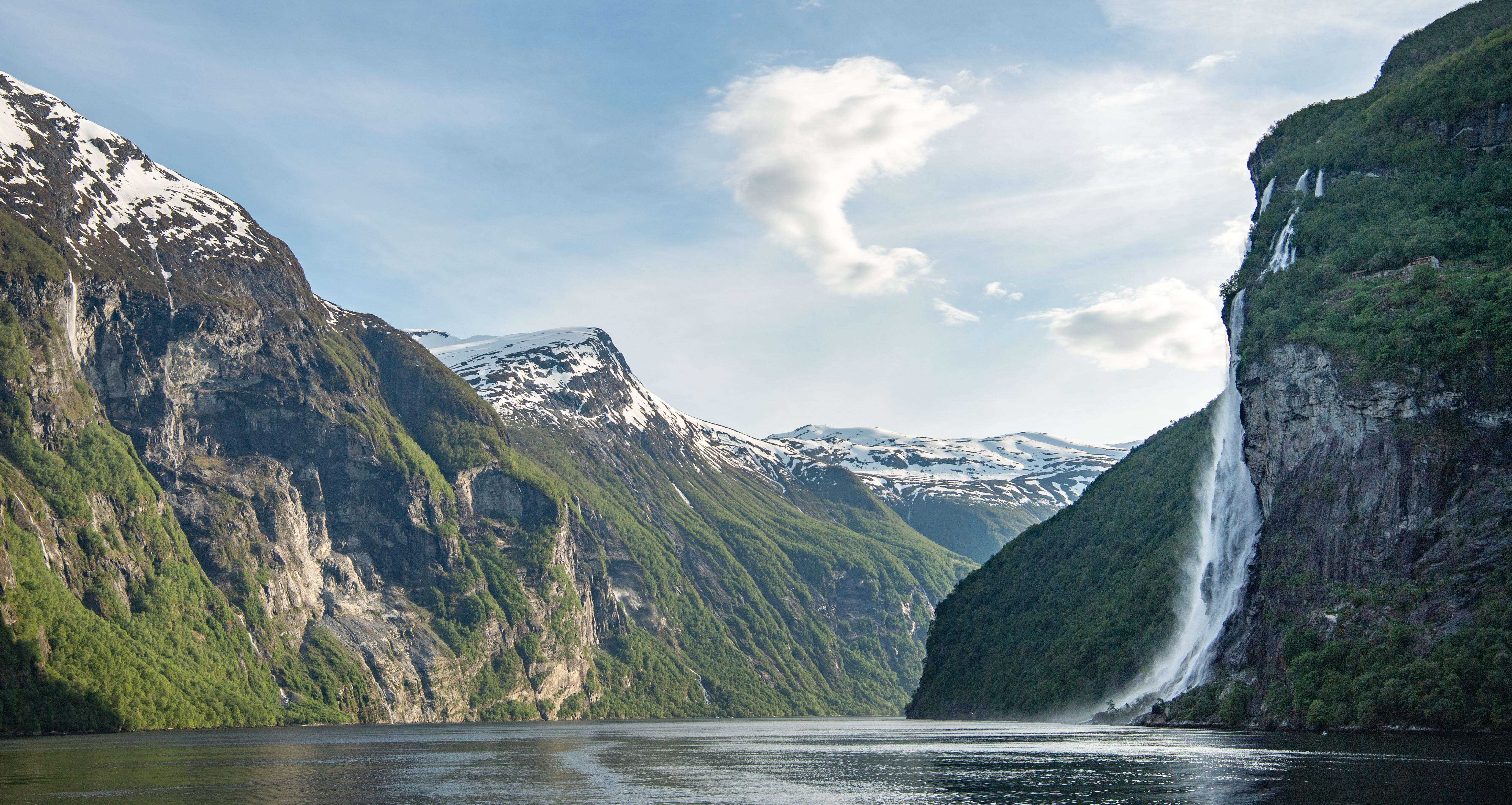 An early summer day at the Geirangerfjord, with a large waterfall and snow on tall mountain peaks