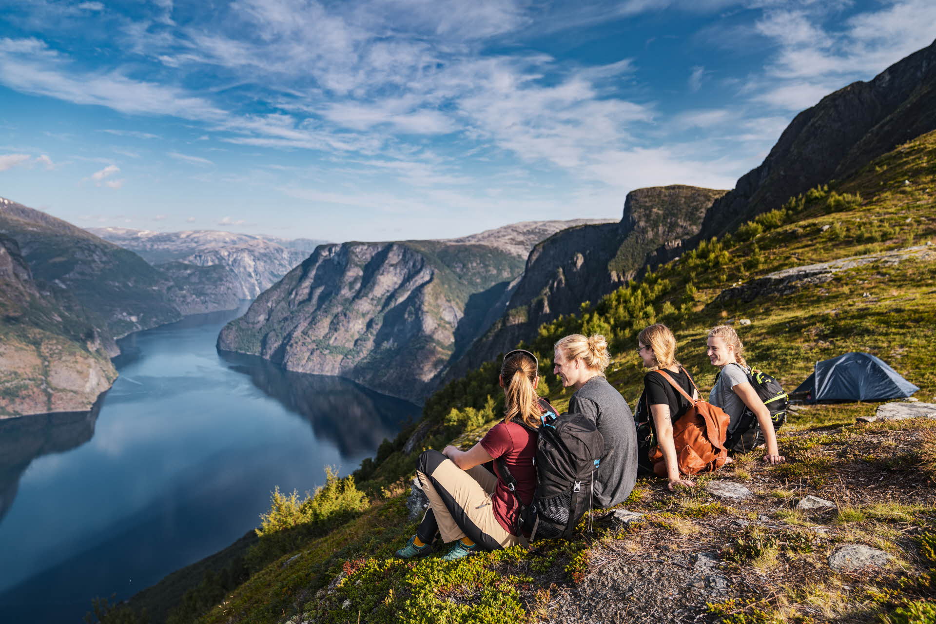 Four people sitting on a mountain ridge looking out over the Aurlandsfjord. 