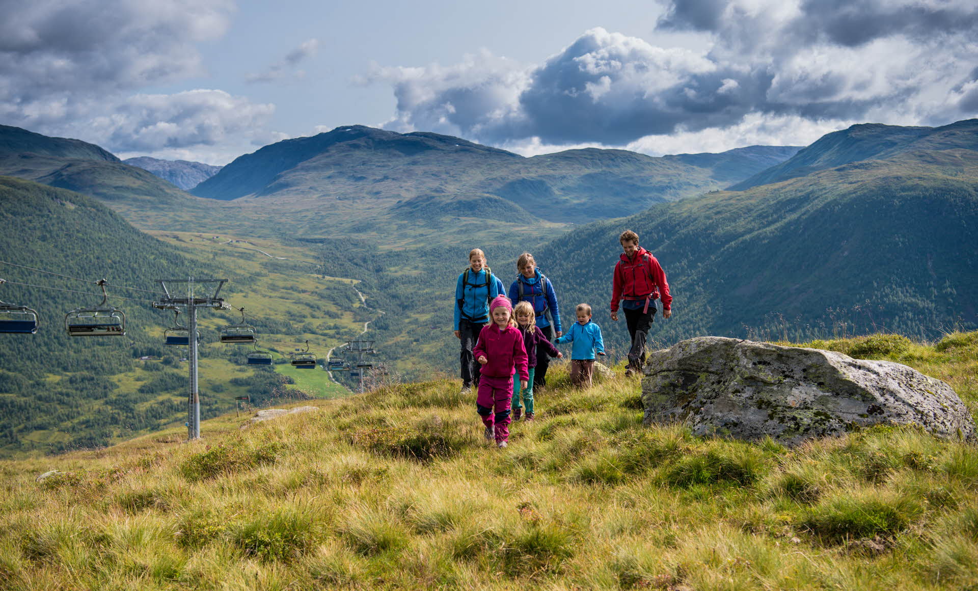 Un grupo de niños y adultos caminando hacia la cámara en las montañas junto al telesilla de Myrkdalen