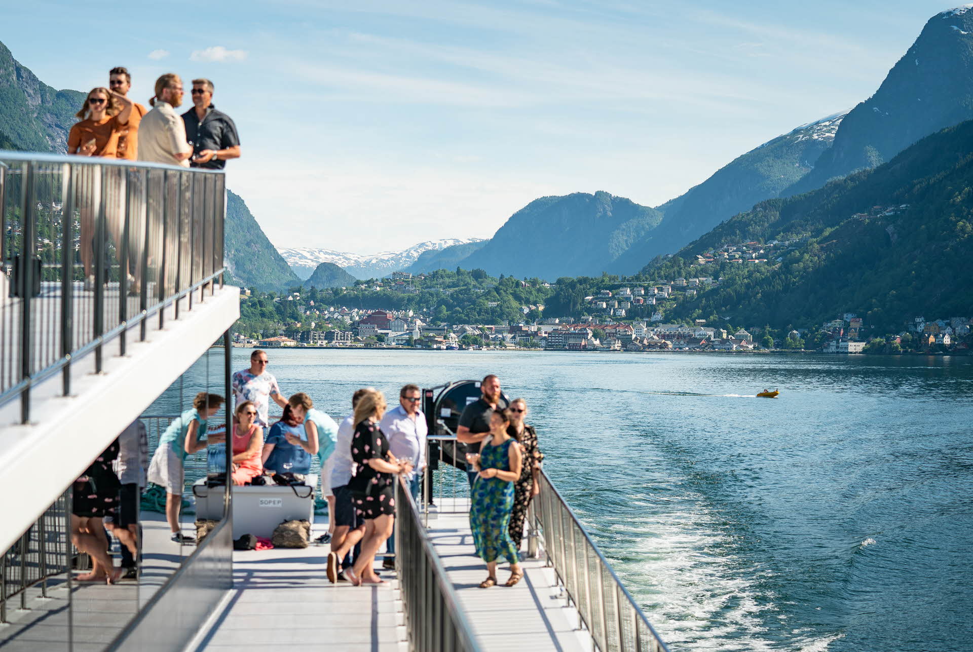 People in light summer wear on the deck of M/S Vision of The Fjords sailing out of Odda