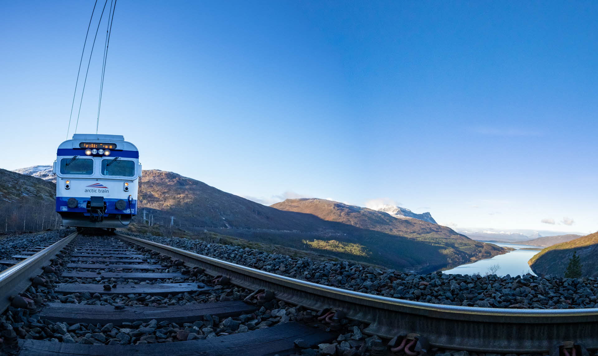 Et blått lokomotiv på jernbanespor over Ofotfjorden