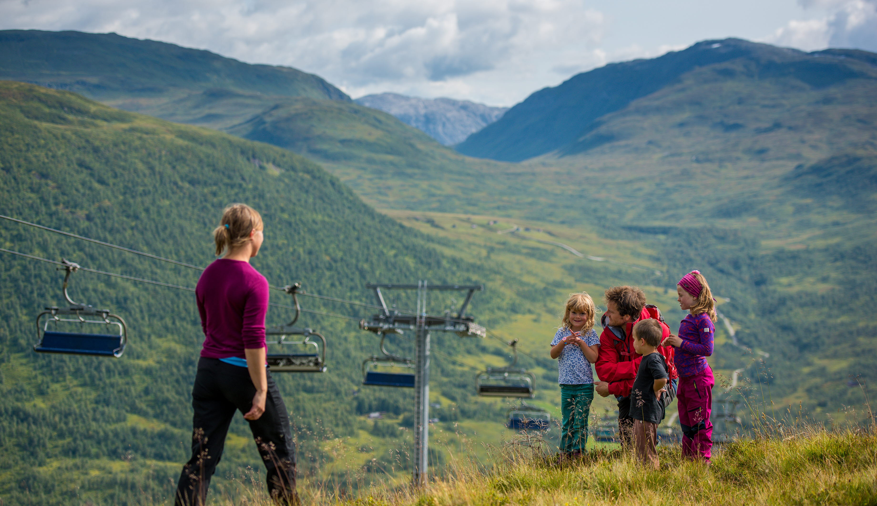 Une femme marchant en direction d’un homme et de trois enfants près du télésiège en montagne à Myrkdalen
