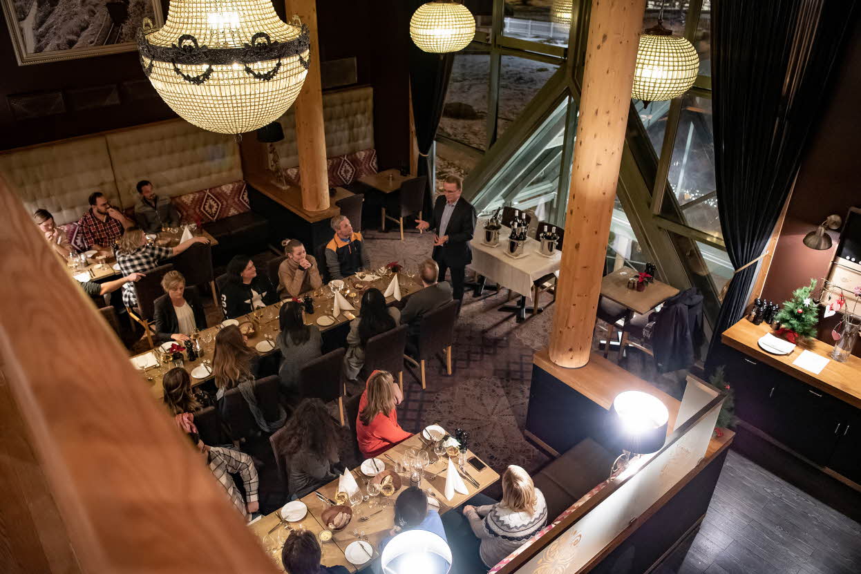Restaurant Arven på Fretheim Hotel sett ovenfra. Gjester sutter rundt bordene, en mann presenterer maten
