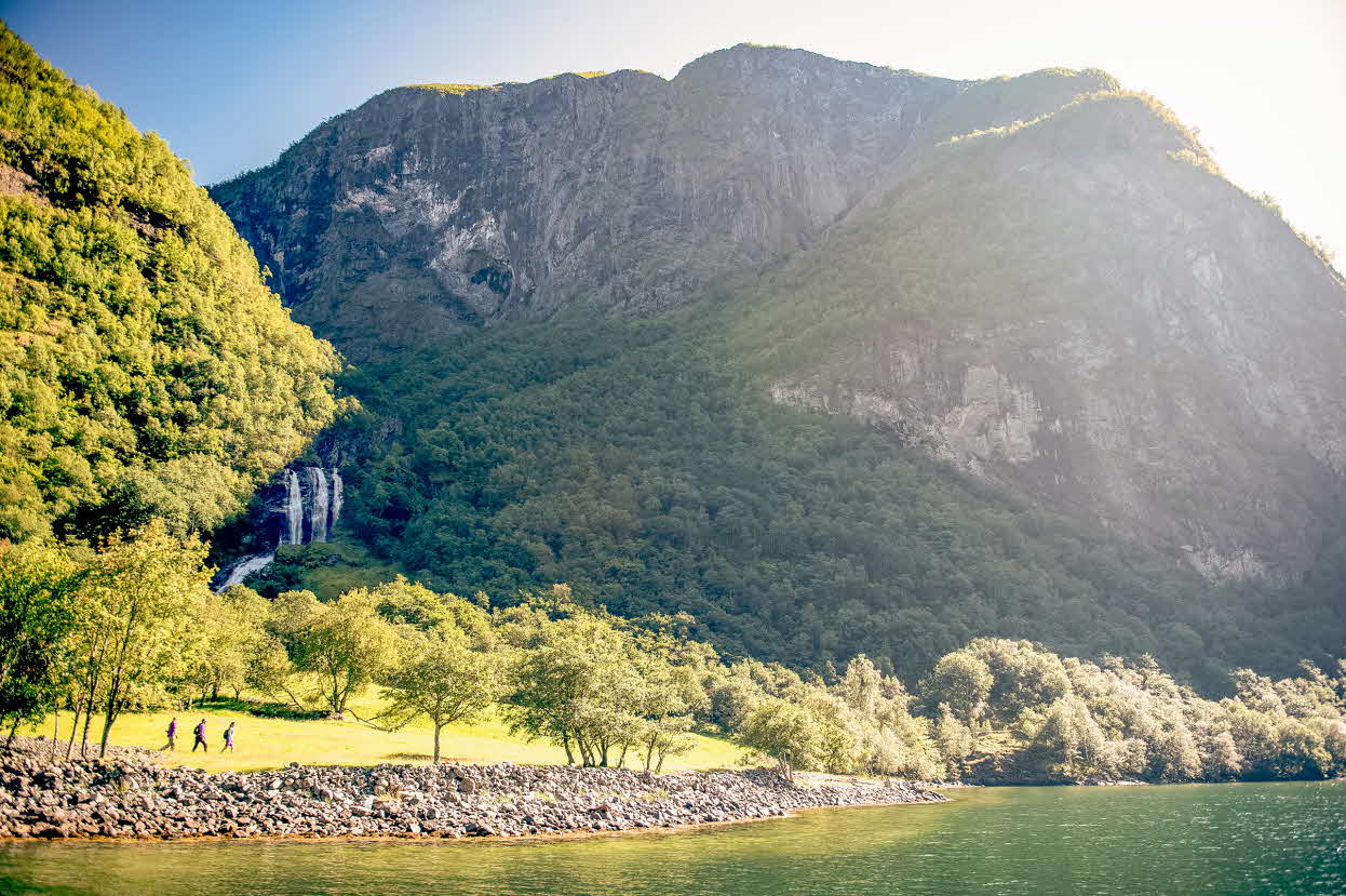 Hikers on the old Kongevegen at the Nærøyfjord, with a waterfall in the background