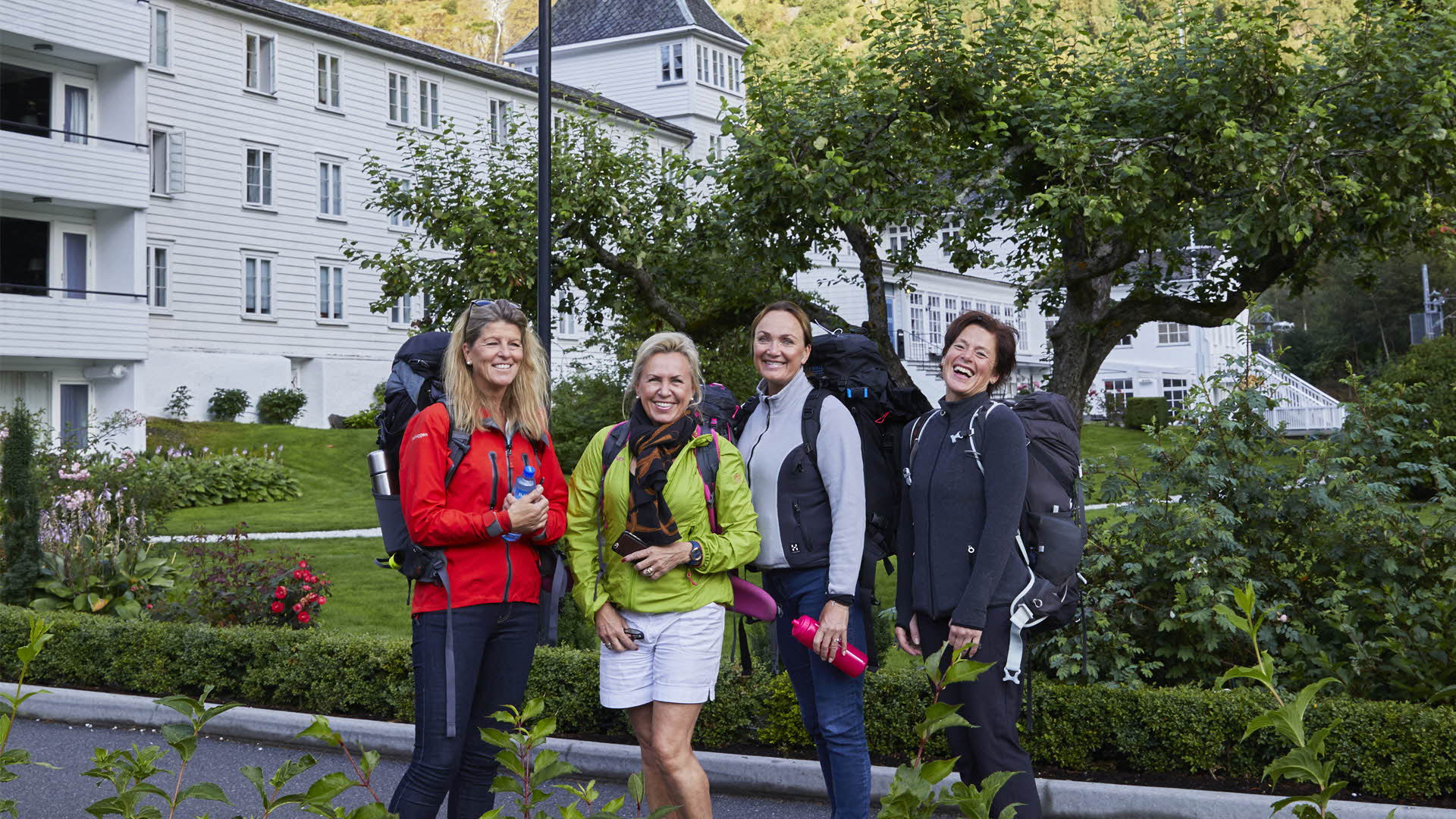 Quatre femmes en tenue de randonnée posant, souriantes, devant le Fretheim Hotel.