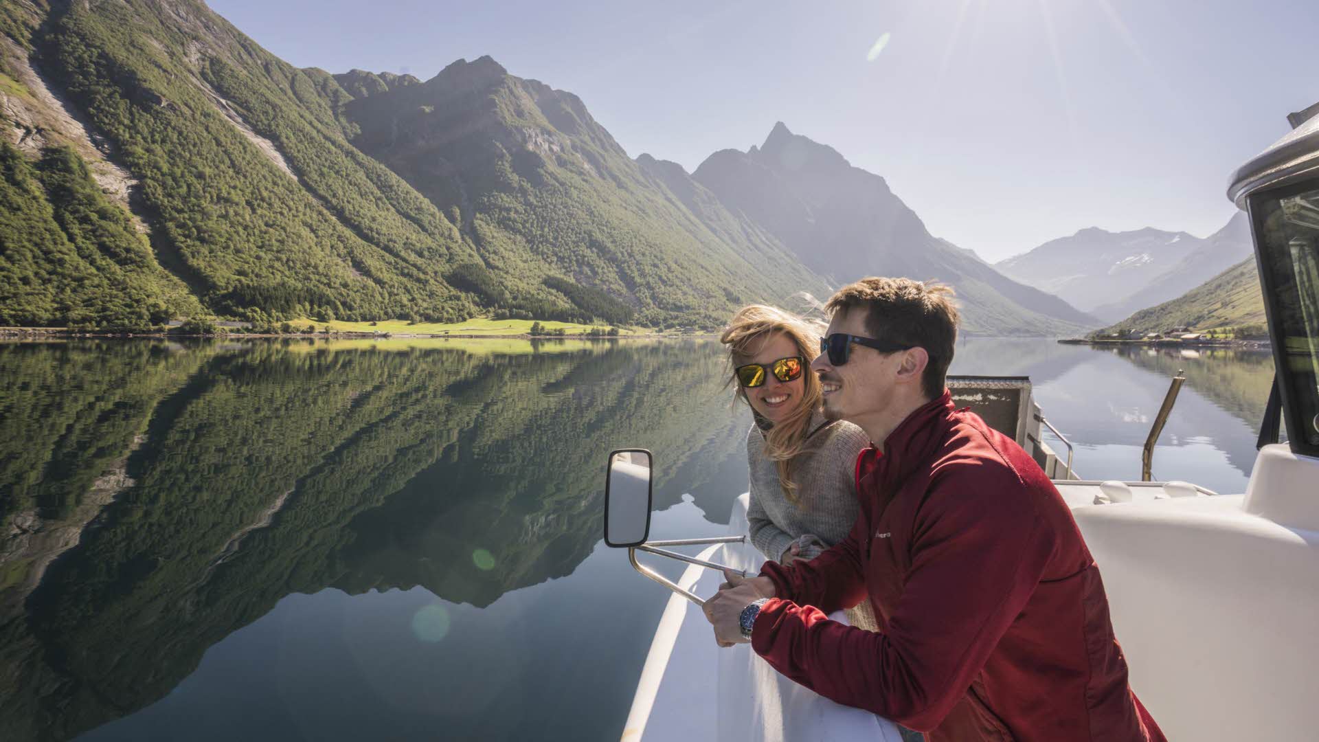 Mann og kvinne står på båten på Hjørundfjorden