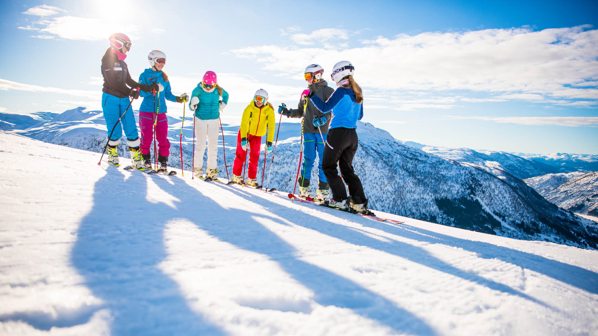 6 Personen in Alpinski-Ausrüstung stehen an einem klaren, sonnigen Tag an den Skipisten des Skiresorts Myrkdalen, mit Blick auf die Winterlandschaft