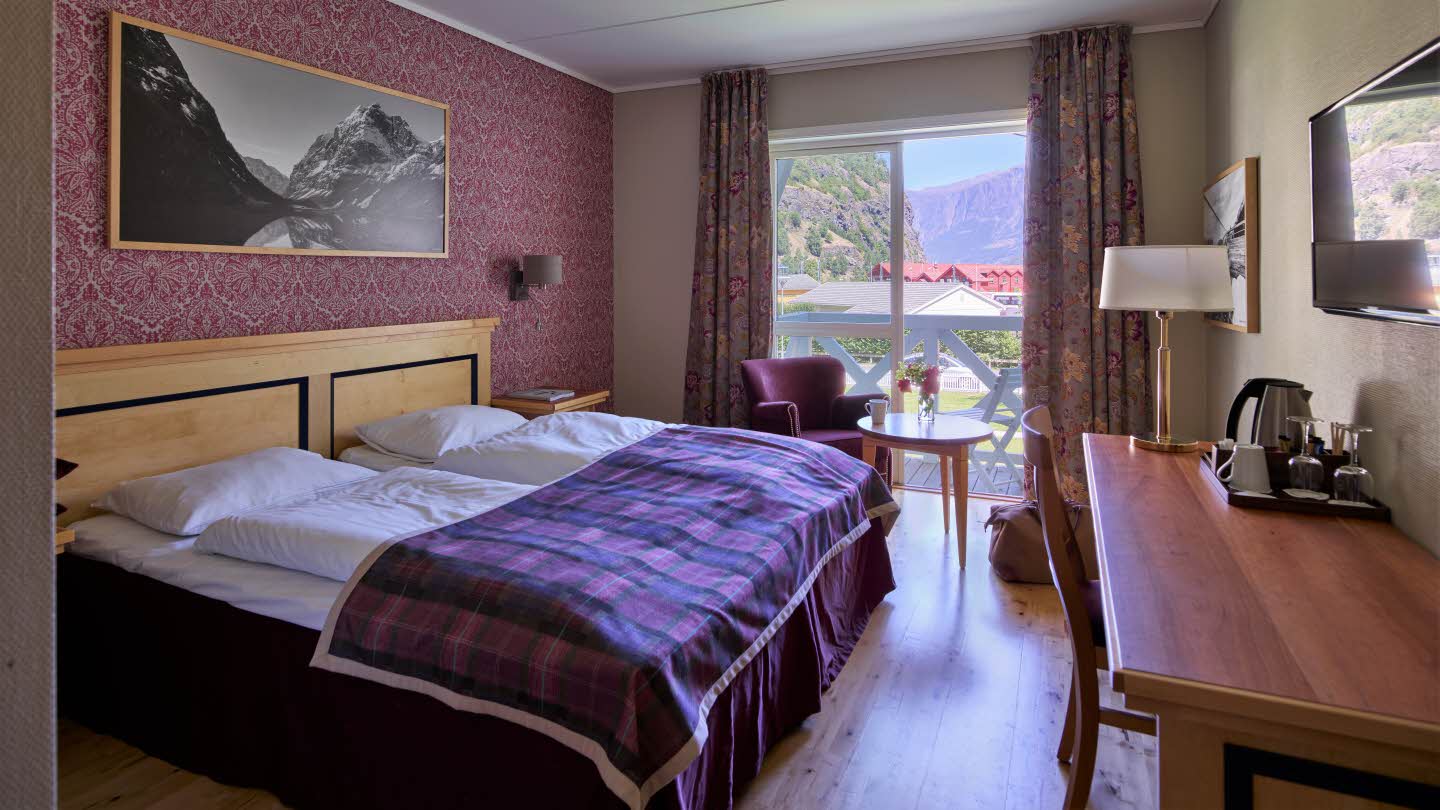 Interiør av dobbeltrom med balkong mot fjorden på Fretheim Hotel. 