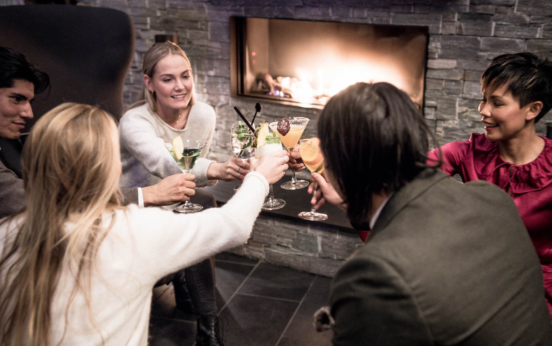 To menn og tre kvinner skåler smilende med drinken i Salto Lobbybar
