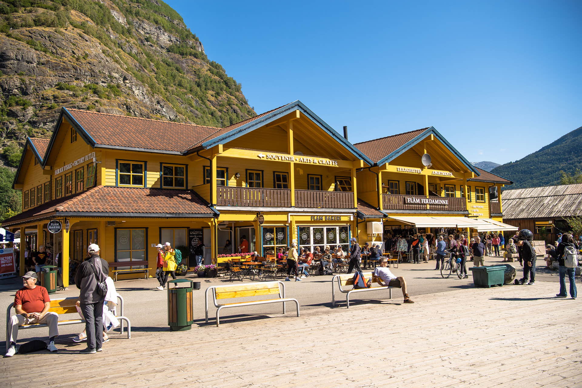 A summer day at the quayside in Flåm, with people sitting outside the Flåm Bakeri
