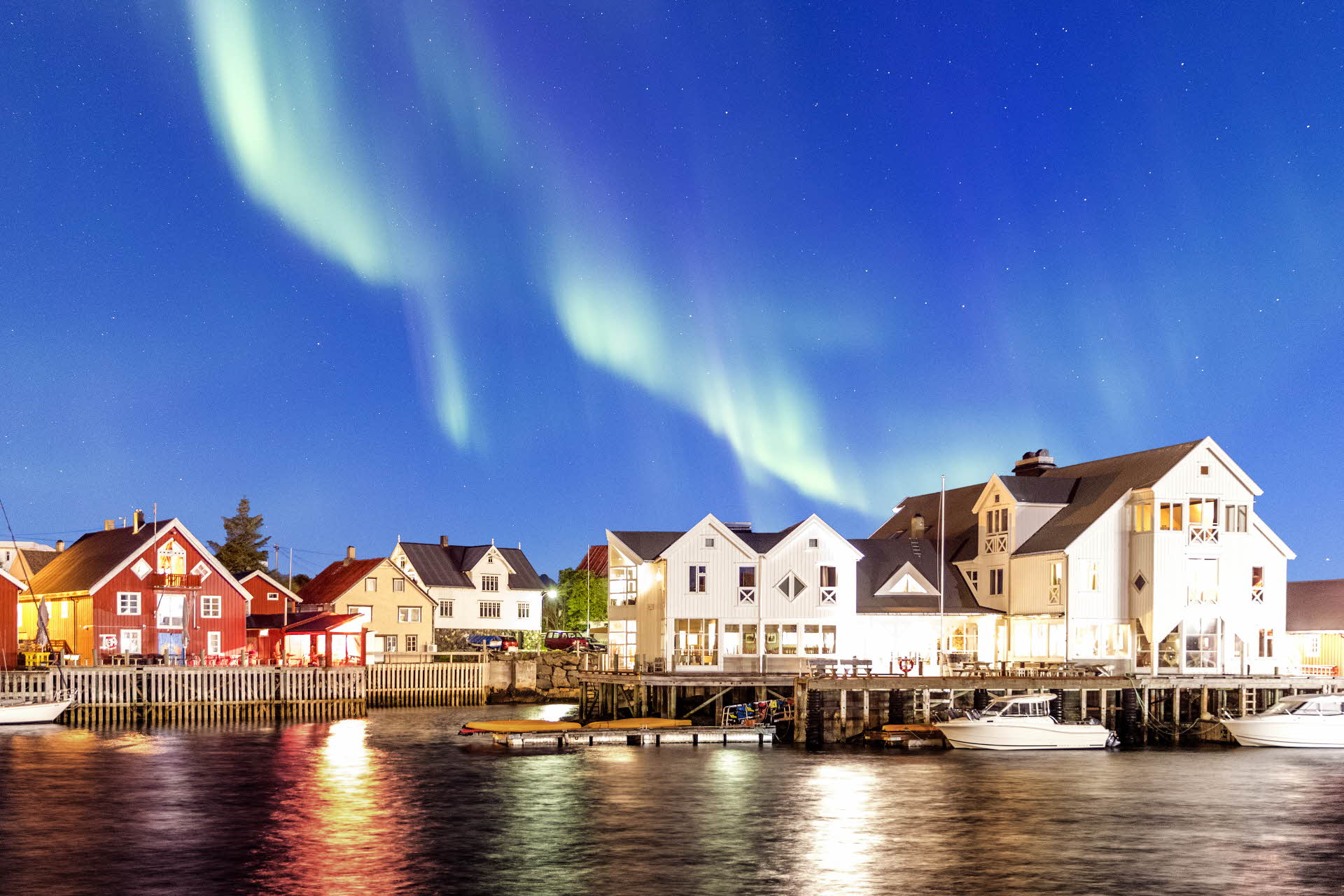 Aurora boreal en el cielo sobre el muelle y el Henningsvær Bryggehotell. 