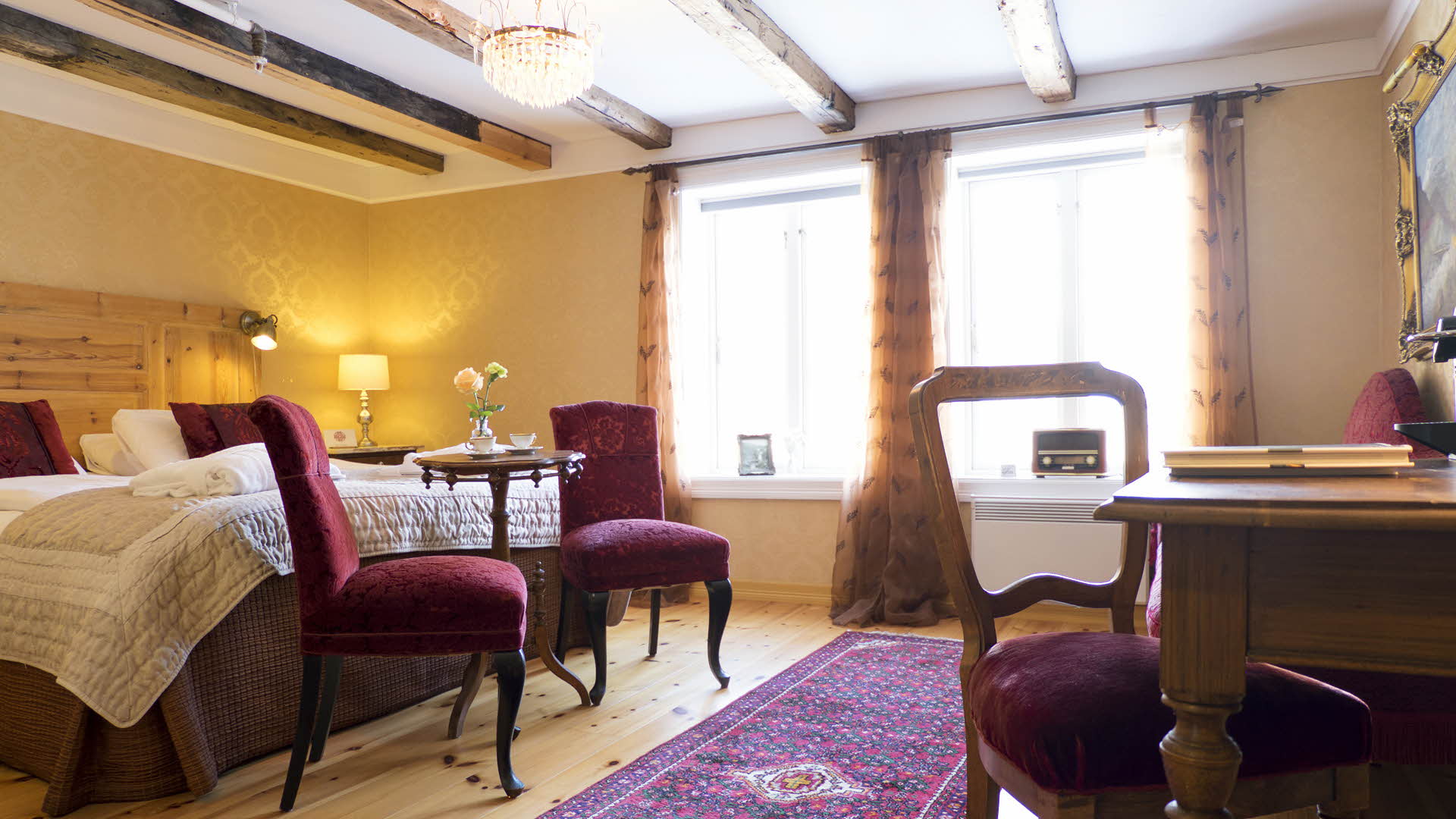 Historisches Zimmer mit gelben Wänden und weinroten Polstermöbeln im Hotel Fretheim in Flåm