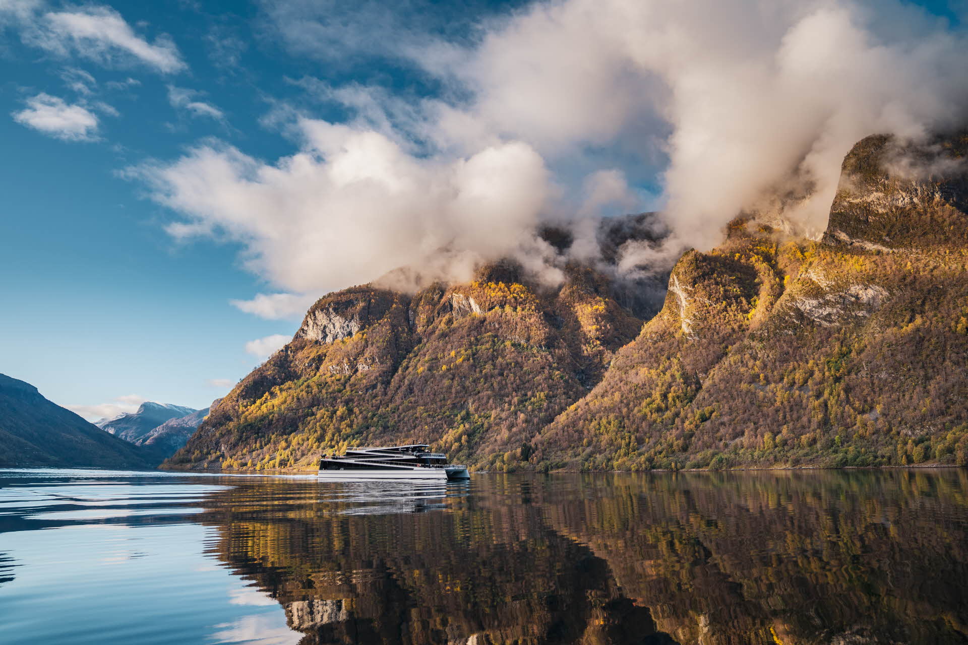 Panorama view of woman standing in the front and middle of Future of The Fjords sailing through Naeroyfjord in summer