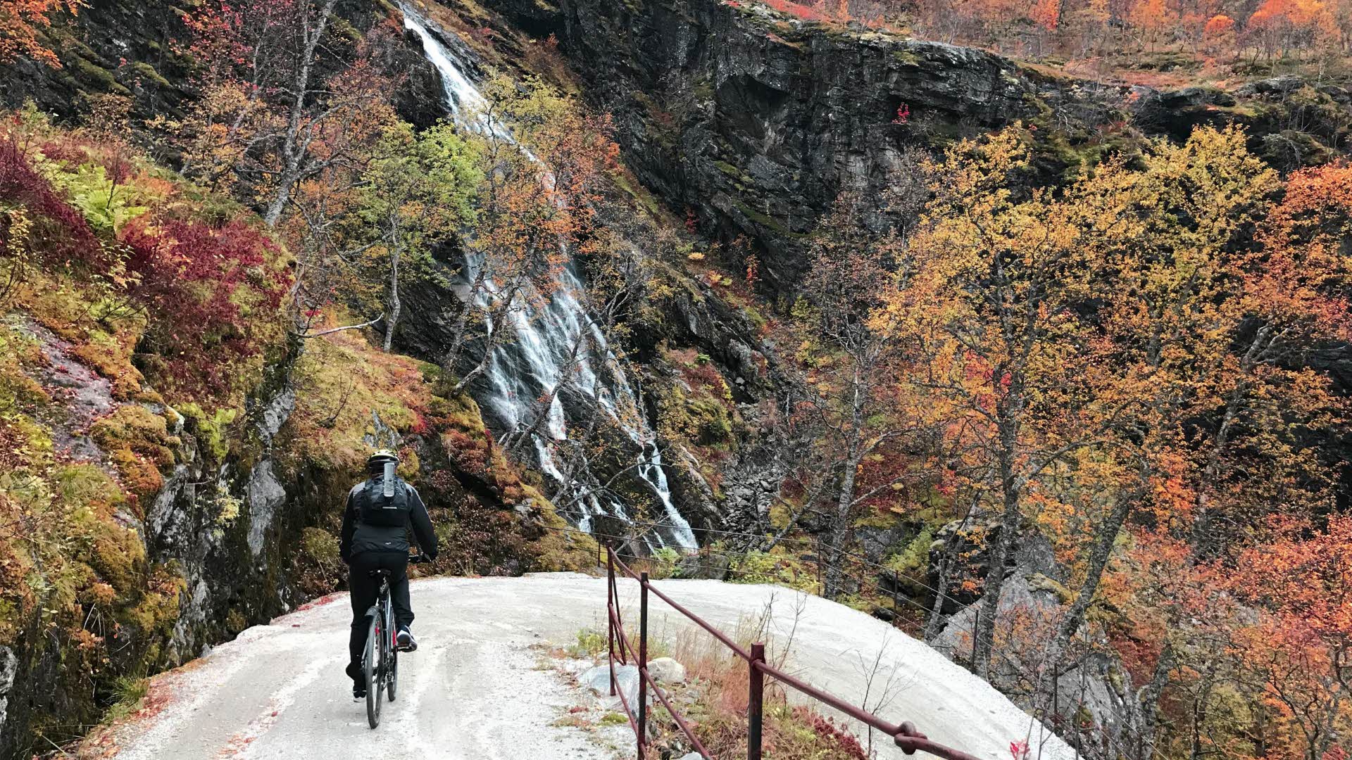Un hombre descendiendo en bicicleta por una empinada colina por la ruta de los peones camineros en otoño