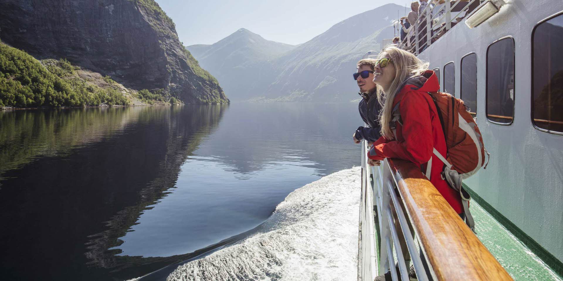 A woman and a man looking at the mountains on a fjord cruise on the Geirangerfjord